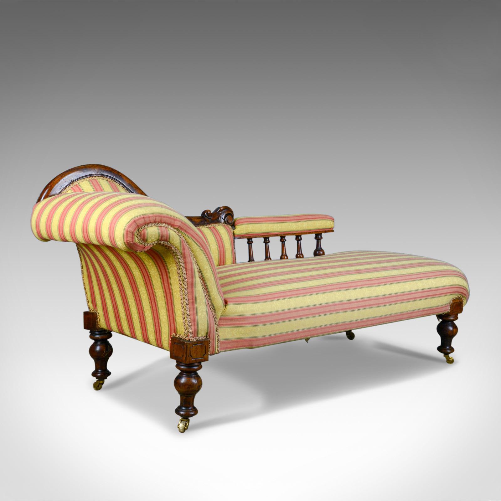 This is a left handed antique chaise longue, an English, Victorian scroll-end day bed on mahogany frame dating to circa 1870.

Raised on stout, squat, turned mahogany legs and frame
Riding upon solid brass castors all round
Appealing sinuous