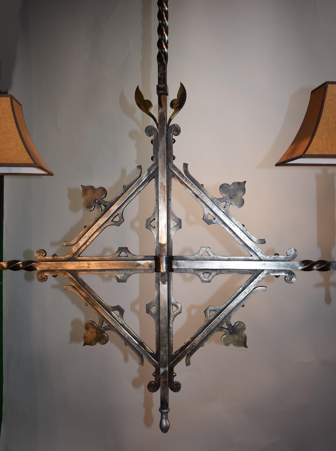 Lustre insolite en fer de style gothique français à deux lumières avec abat-jour, idéal pour un îlot de cuisine ou une table de billard. Quatre disponibles. Le luminaire mesure 58 pouces de long x 48 pouces de large avec les abat-jours, il mesure 40