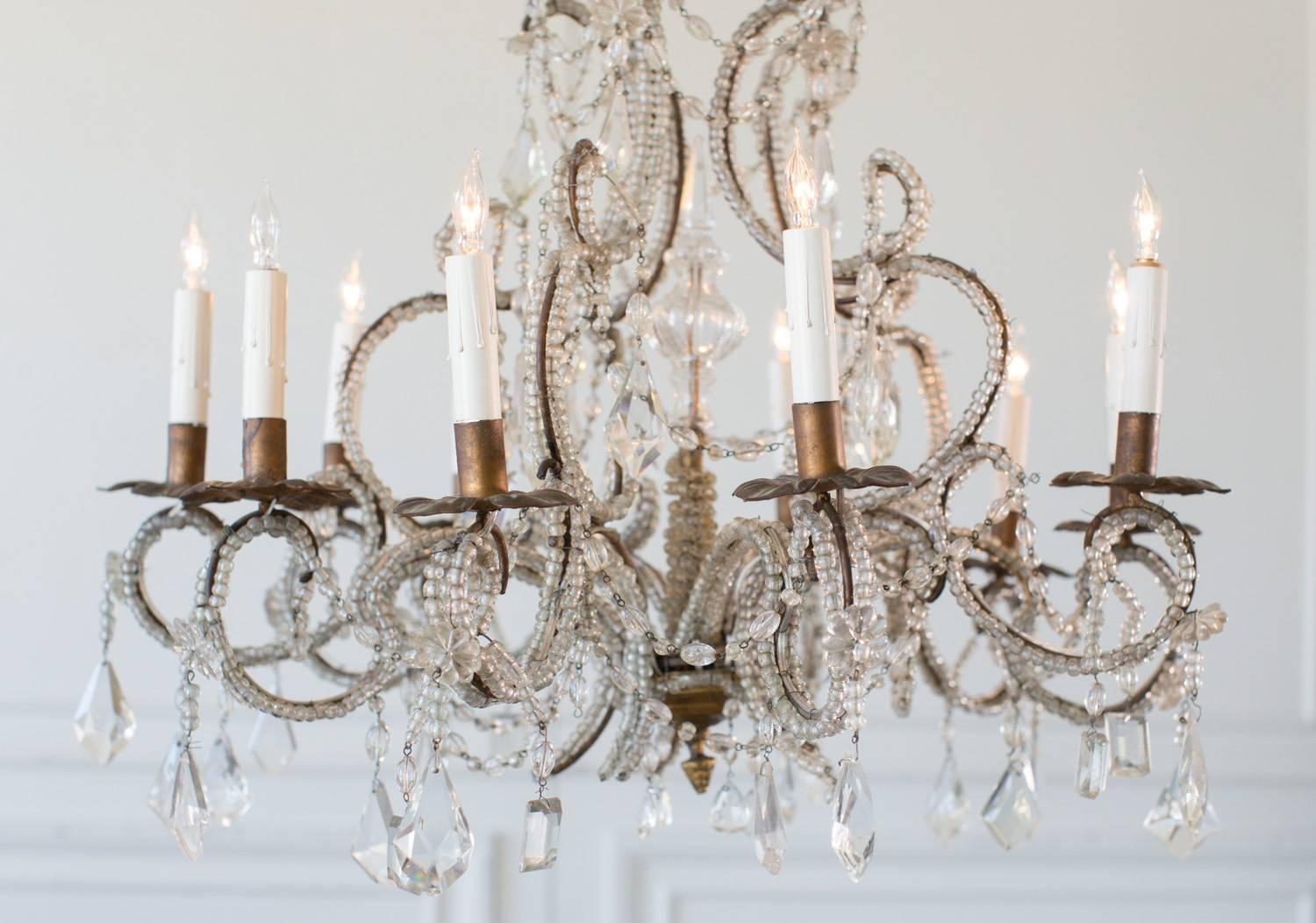 Striking, beaded antique chandelier with eight arms. The frame of this unique light is entirely strung with an abundance of small, glass beads that Cascade from top to bottom. A multitude of crystal shapes enhance the complexity and grace of this