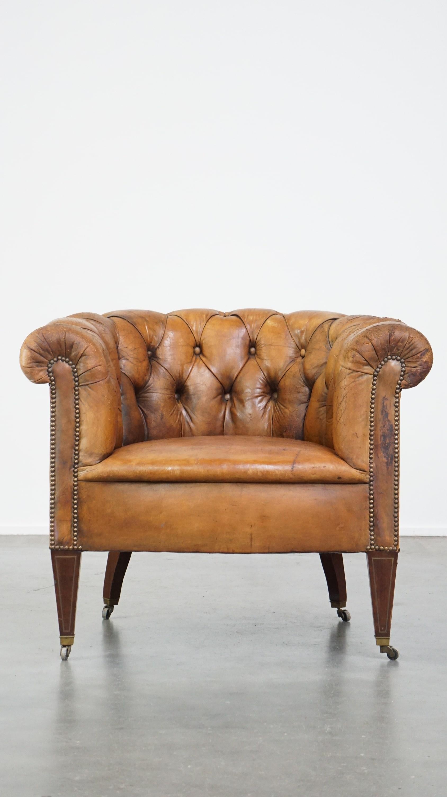 Offered this antique, characteristic sheepskin chesterfield club armchair on wheels.

This antique sheepskin chesterfield club armchair has a striking character. It is equipped with a fixed seat cushion and has a comfortable seat. However, this club