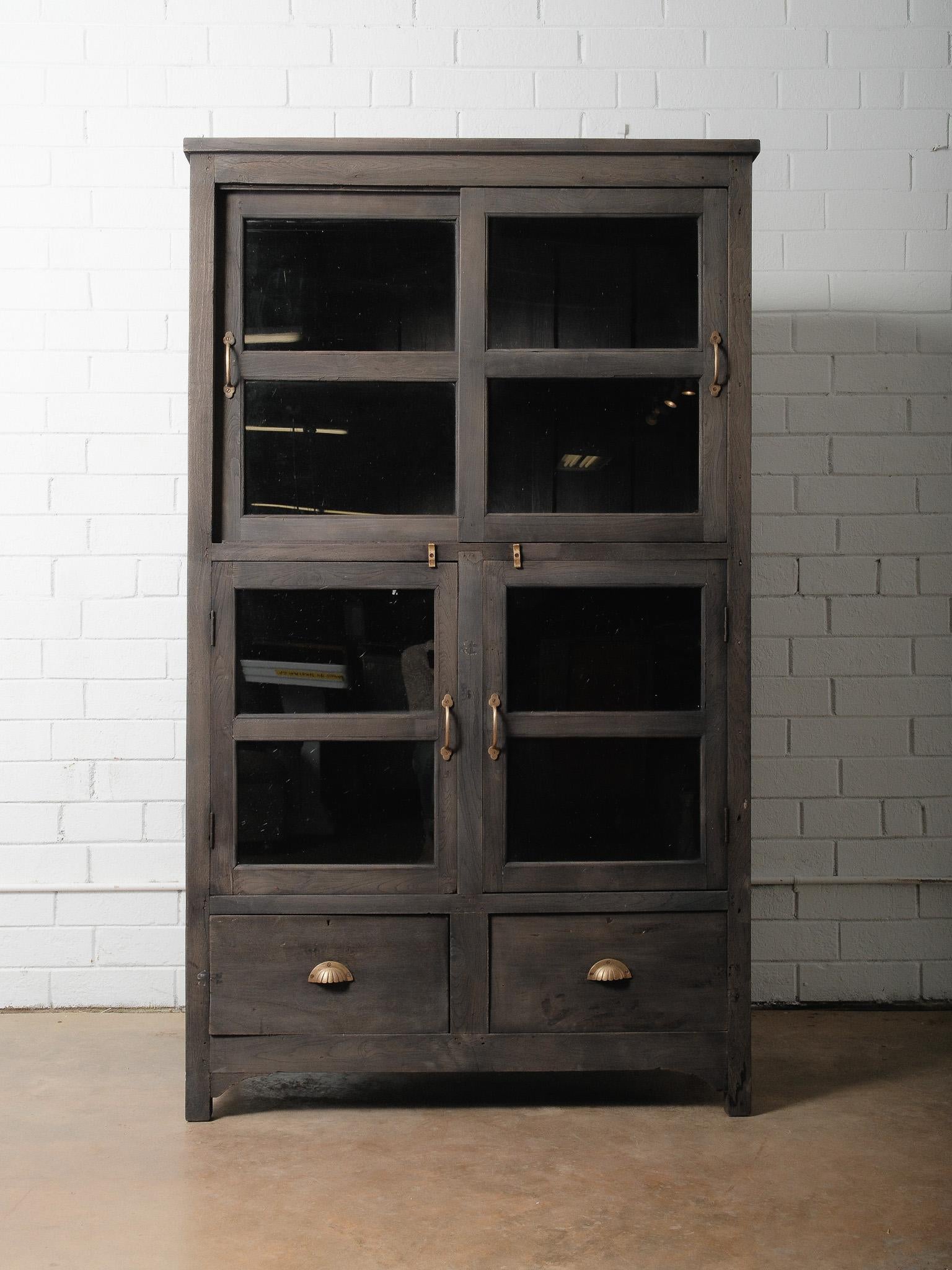 Un remarquable meuble en bois antique fini anthracite comprenant quatre portes vitrées et deux tiroirs inférieurs profonds avec des poignées classiques en laiton. Cette pièce magnifiquement vieillie présente une patine anthracite sombre et altérée