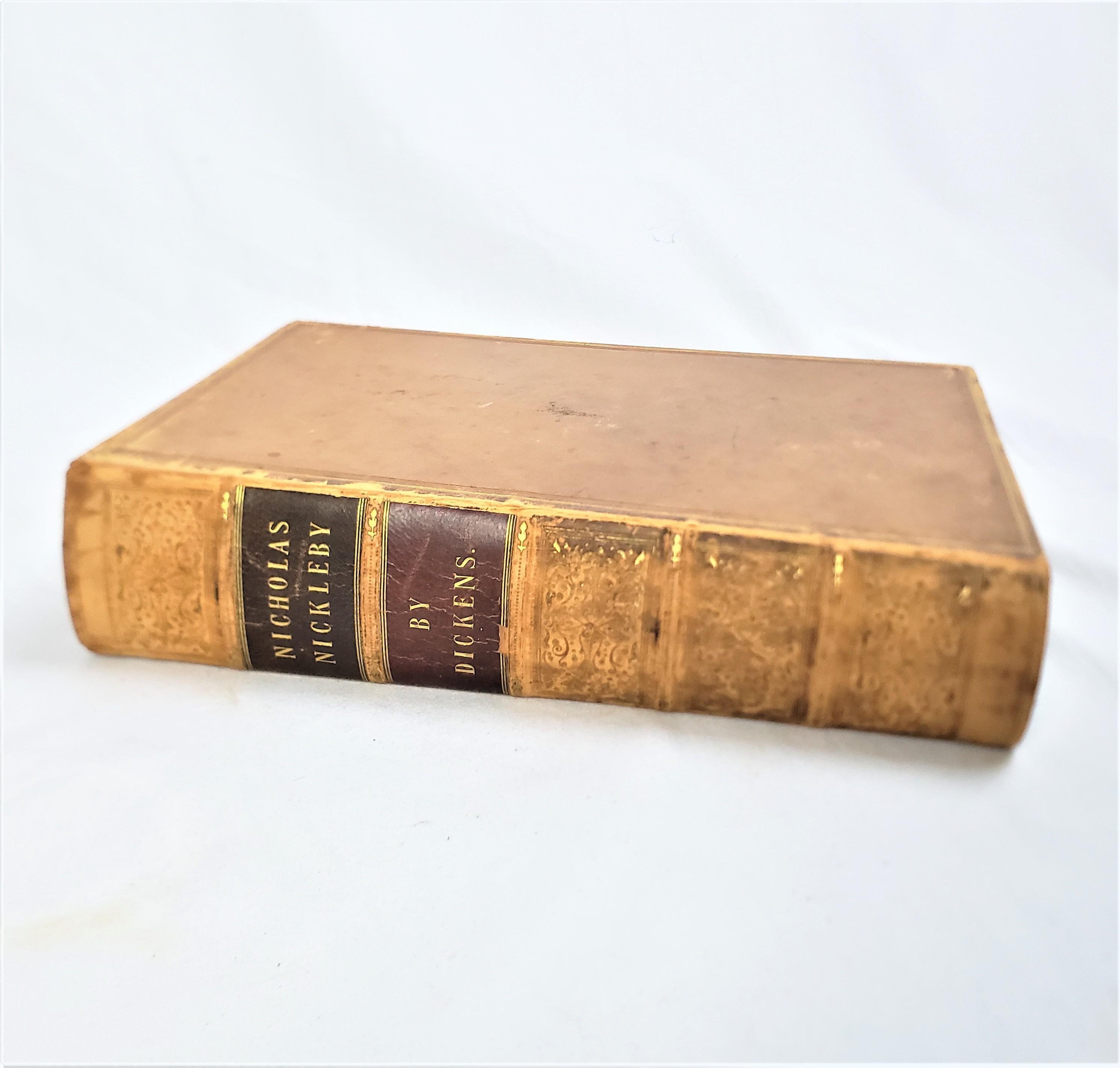 Ce livre ancien de 1ère édition intitulé Nicholas Nickeby a été écrit par Charles Dickens et publié par Chapman and Hall en Angleterre en 1839 dans le style victorien de l'époque avec des gravures de Hablot.  Knight Browne 