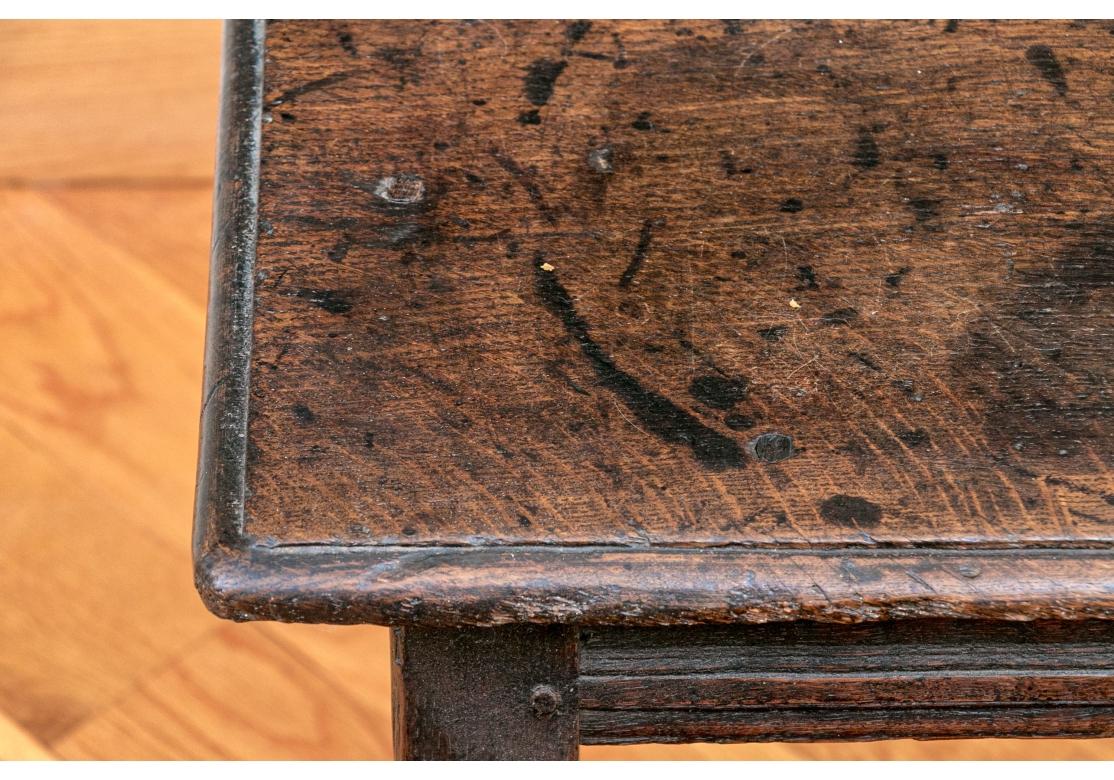 Charles II rectangular sturdy and weighty stool with exposed peg construction, incised edge, decorative carved apron, turned legs conjoined with a box stretcher.

Dimensions: 18