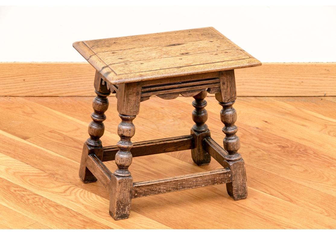 A small Table Stand with fine and deeply turned legs, stretcher base, three plank top and carved apron with scroll accent. The table is very well made and exhibits a fine Golden color to the wood and a soft hand with desirable age patina. 

The