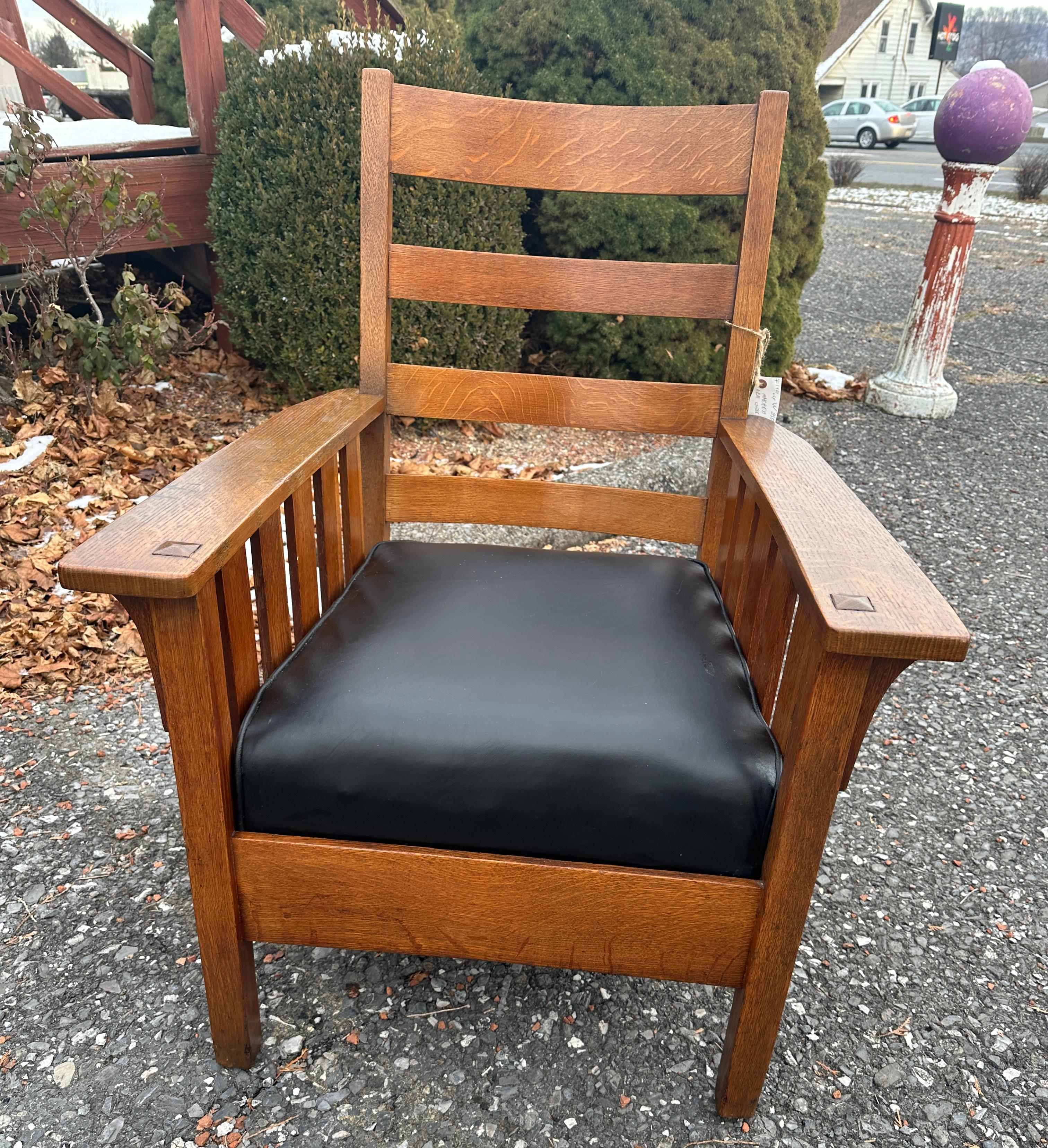 This is an antique Charles Stickley Large Arm Chair with slots under each arm.  The chair has it's original finish. The chair is marked with the Stickley brand as pictured. The seat has been recovered with top quality hand split black leather.  At