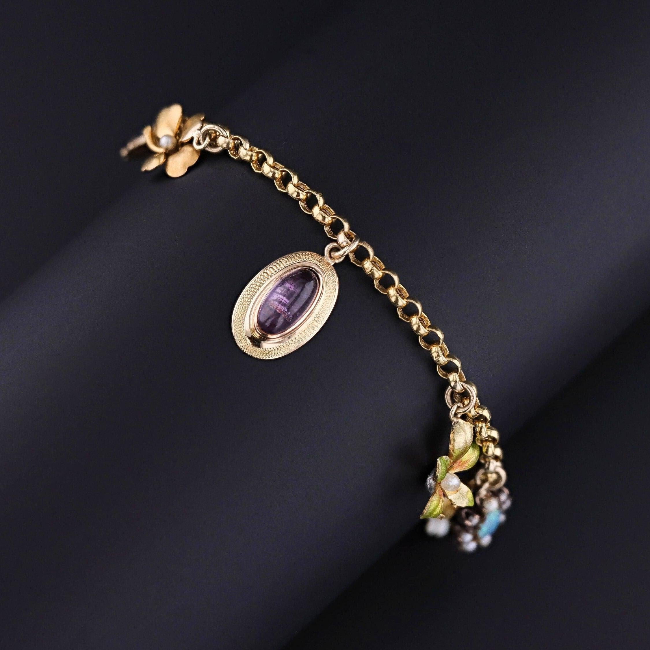 This 14k gold charm bracelet features 8 gemstone and enamel charms -- most were originally antique stickpins (circa 1910). Two of the charms are 10k gold, but the others are all 14k.

The bracelet measures 7 inches long and weighs 7.9 grams. It is