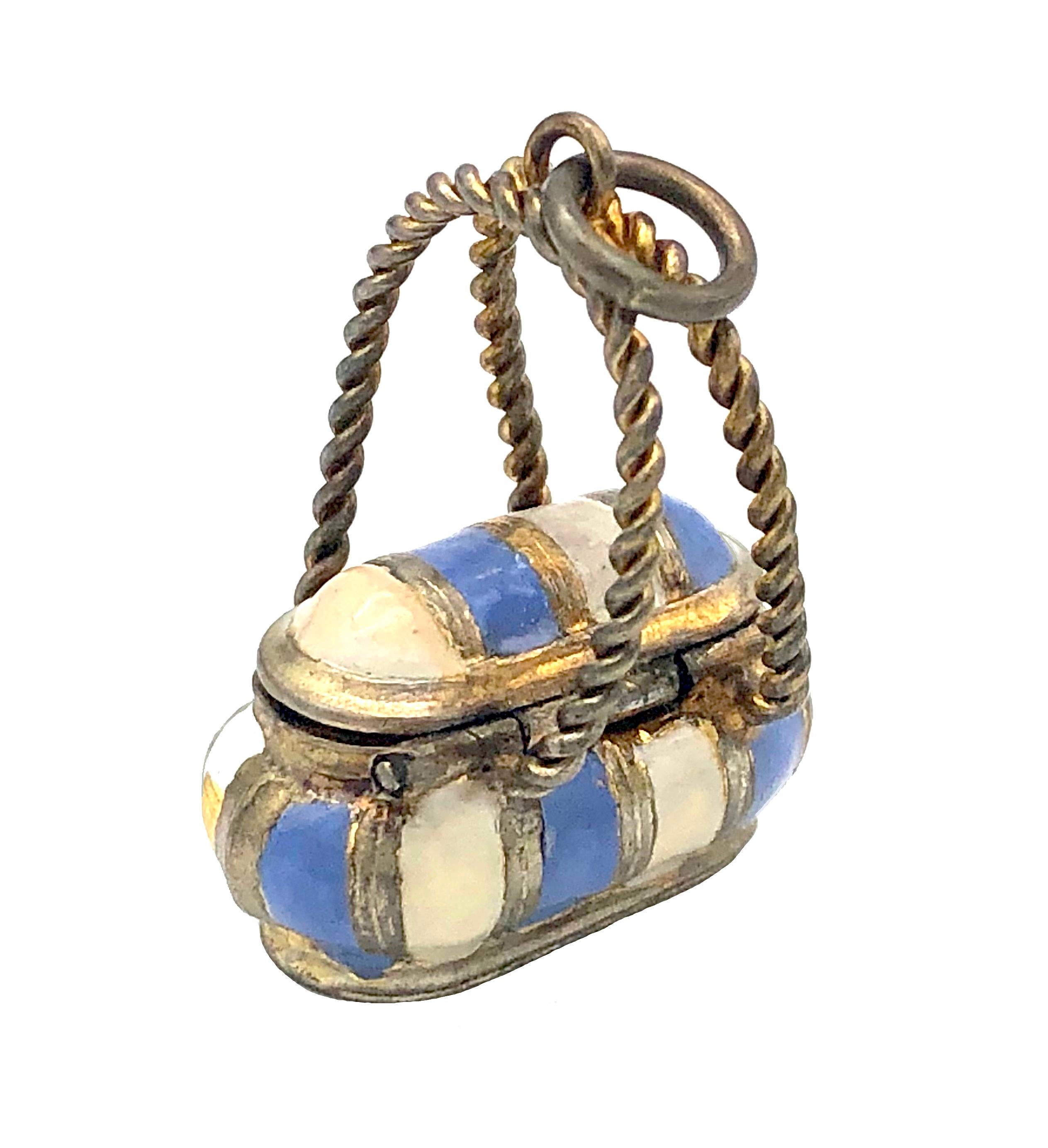 This delightful little pendant in the shape of a basket is made out of guilt metal and decorated with pale  blue and white enamel.  