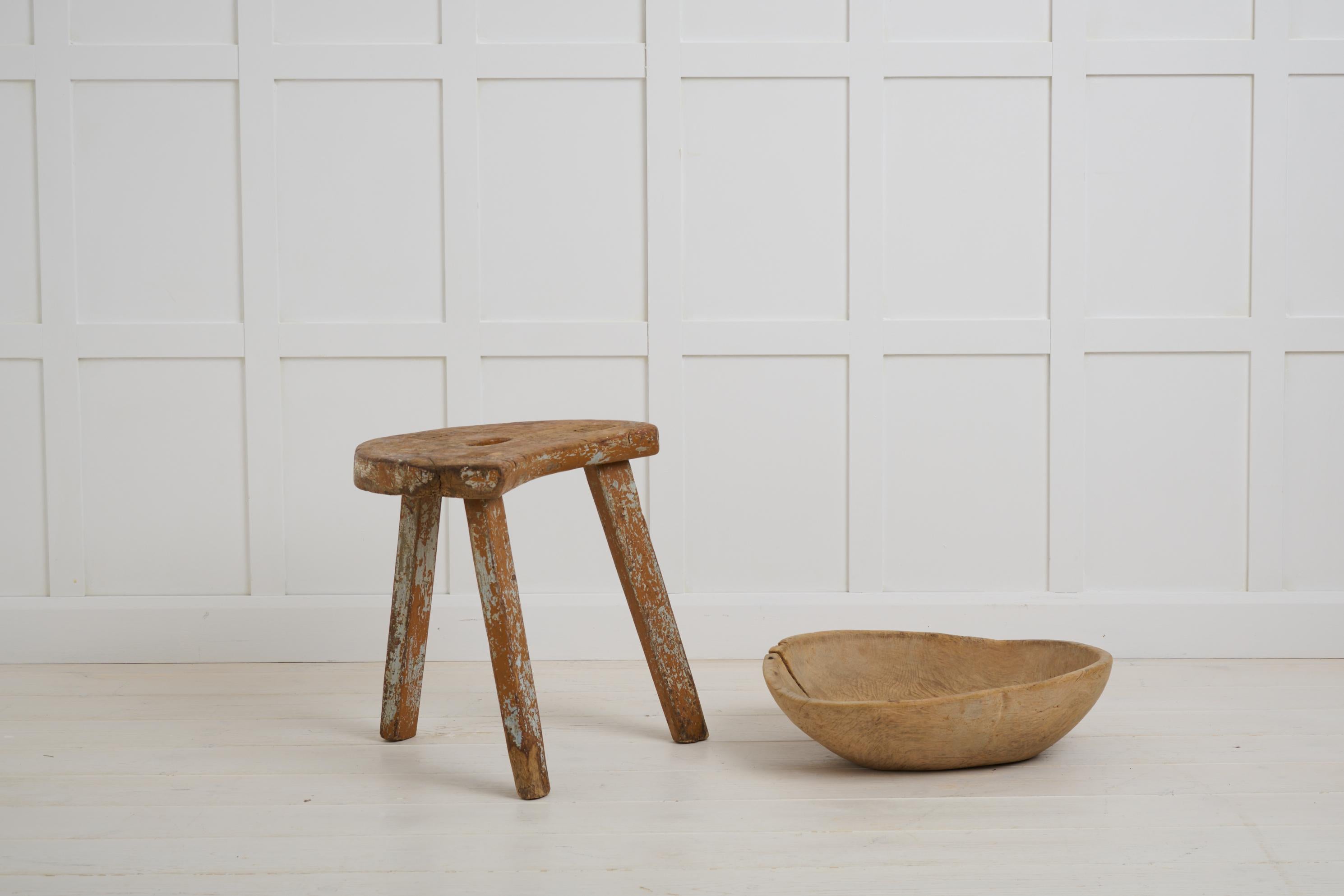 Charmant tabouret d'art populaire fabriqué à la main en pin massif. Ce tabouret a une construction primitive et une forme organique avec une poignée découpée au centre. Fabriqué dans le nord de la Suède vers les années 1840, le tabouret est dans un