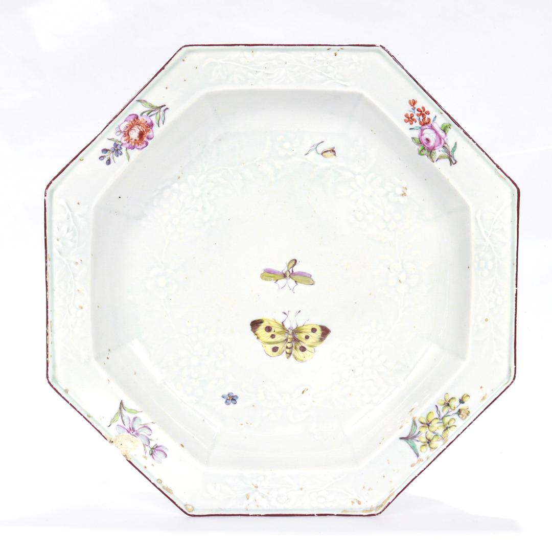A fine antique English porcelain plate.

By the Chelsea Porcelain Factory.

Likely made in the 1750s during Chelsea's Red Anchor Period.

In an octagonal form with Meissen influenced 'Gotzkowsky' manner molding throughout, a painted butterfly and