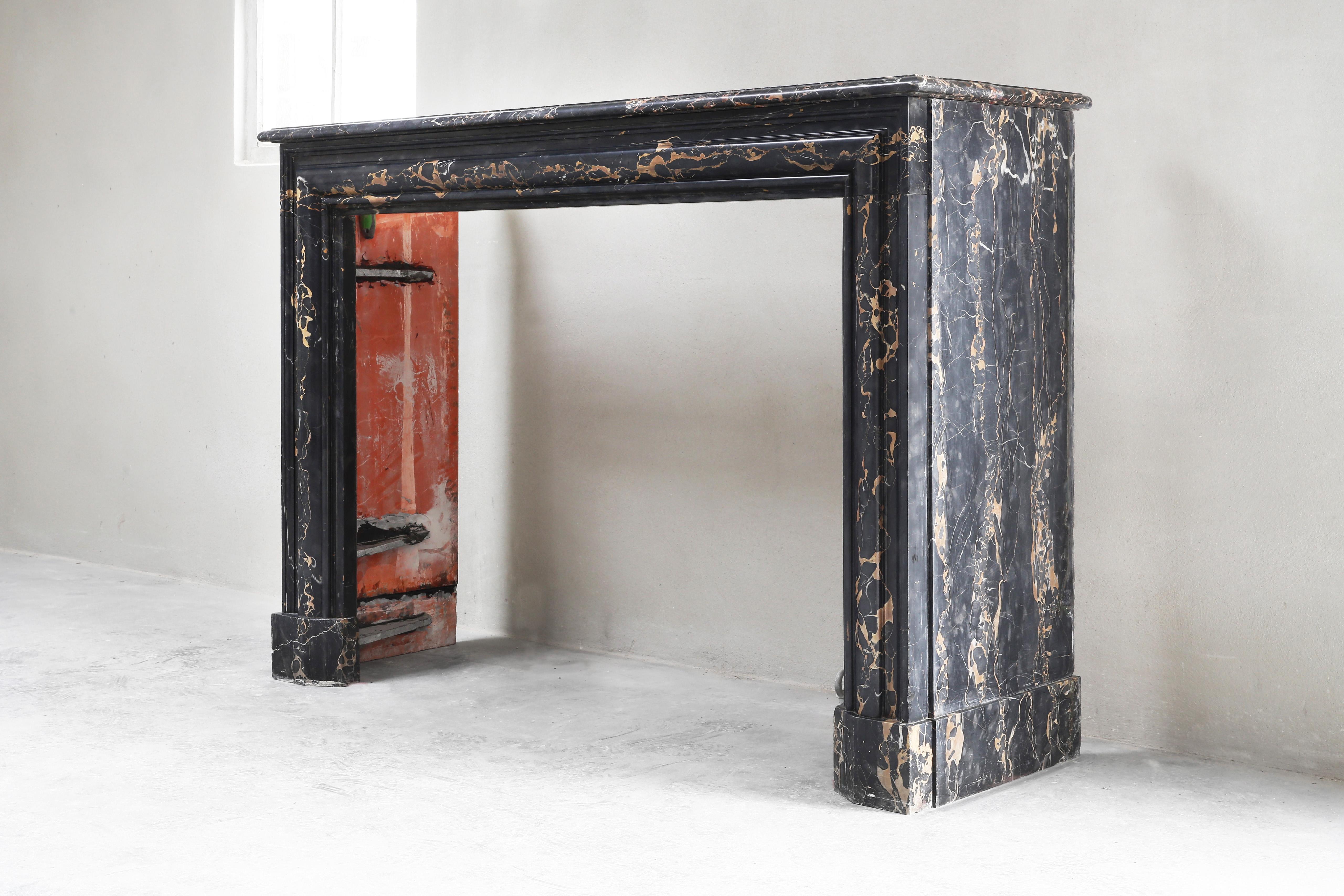 A beautiful antique marble fireplace in the style of Boudain from the 19th century. This type of marble is called Portoro marble and is one of the most elegant Italian types of marble. The black background with golden veins ensures luxury and