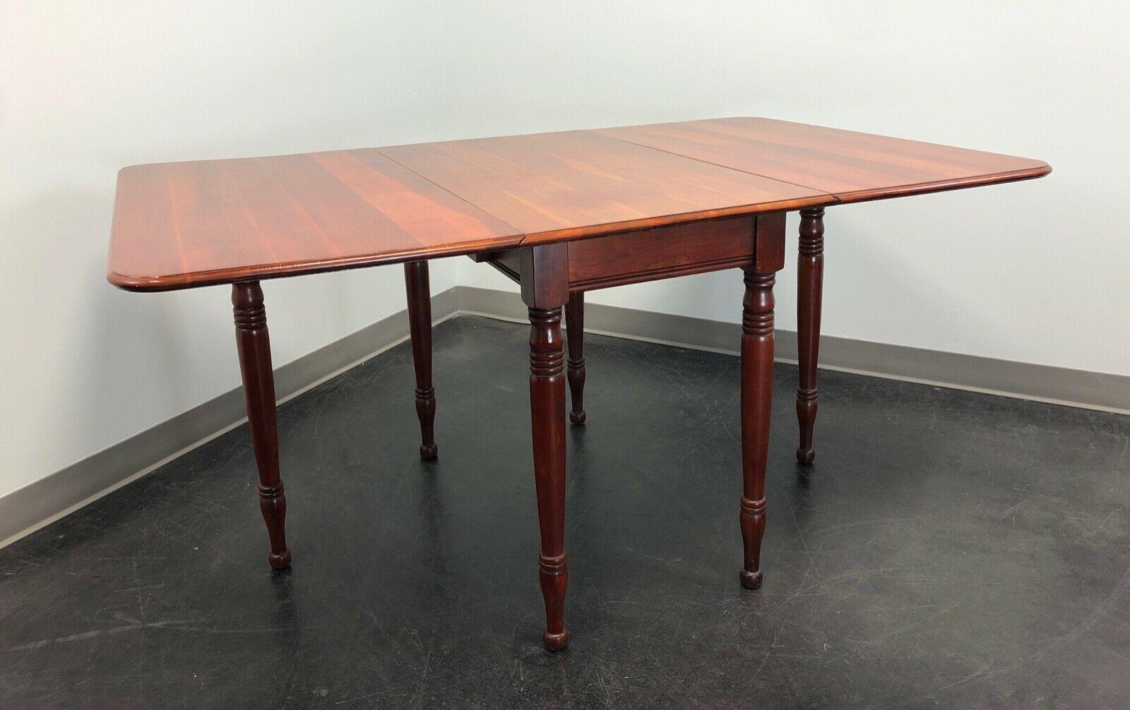 An antique Colonial style gateleg drop-leaf dining table, no makers mark. Solid cherry, a center apron and six turned legs, two being gateleg that swing out to support the drop leaves when raised. Made in the USA, in the late 19th - early 20th