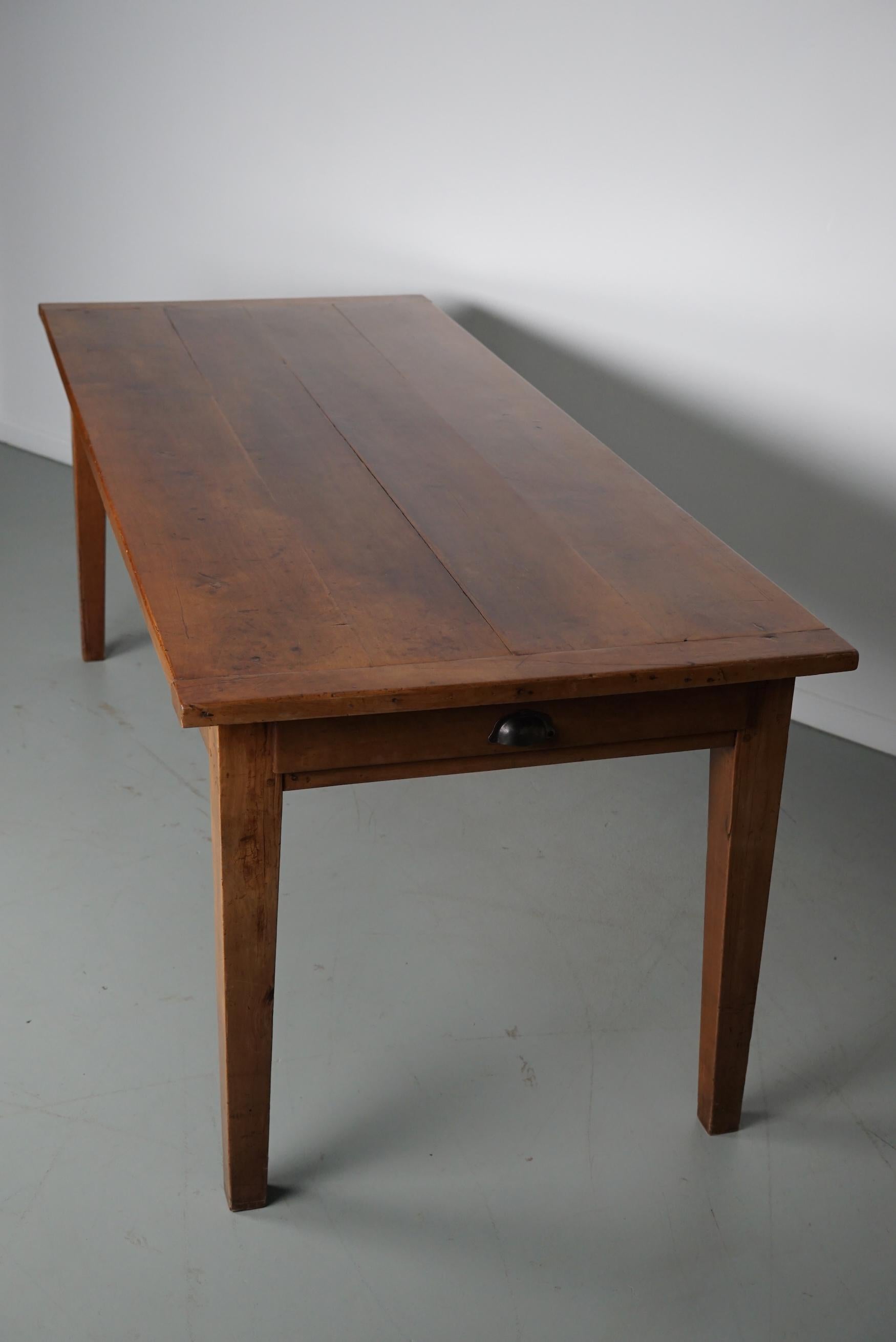 Cette table élégante a été fabriquée dans le sud de la France au début du 20e siècle. Le plateau de la table est en bois fruitier avec de magnifiques veinures. La couleur est très chaude et la table présente de nombreuses marques d'utilisation,