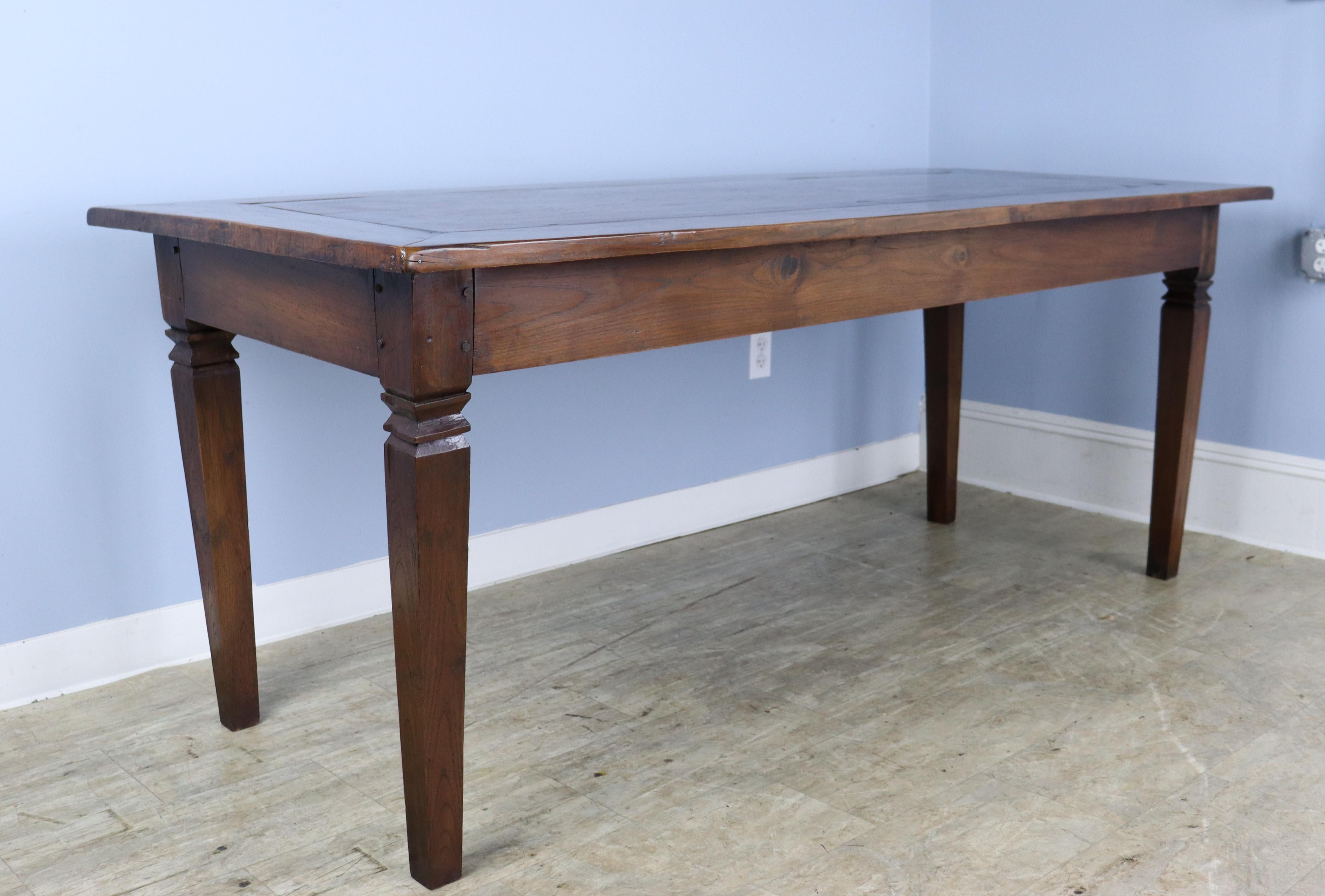 An elegant cherry farm table with carved detail at the top of the legs and a well constructed mitred top. Apron height of 25.5 inches is very good for knees and there are 67.75 inches between the legs on the long side. There is some old wear along