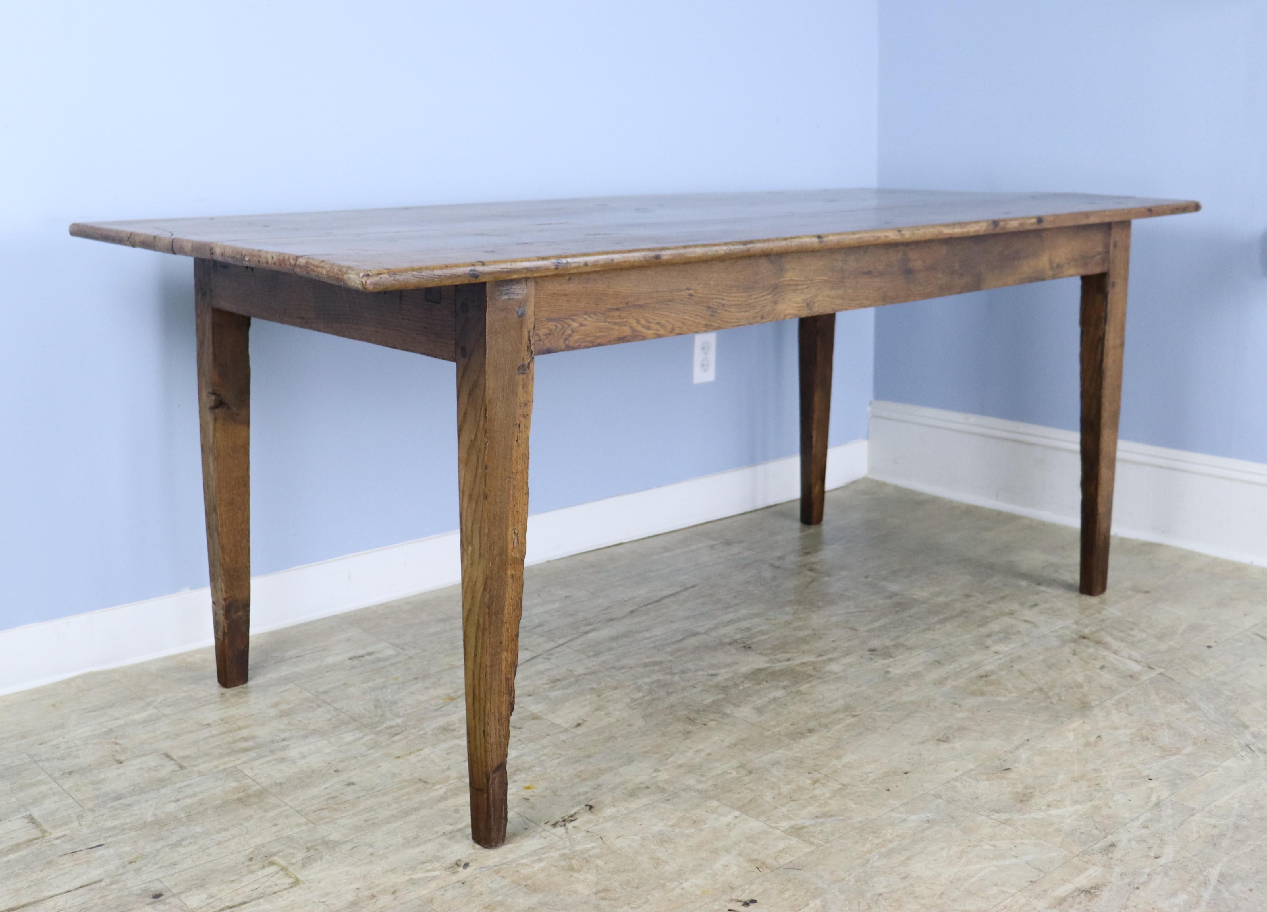 A good country cherry farm table with an oak base.  Classic tapered legs, pegged nicely at the apron. The top has a warm glowing patina with attractive grain and some very interesting old wear. The apron height of 24.75 inches is good for knees and
