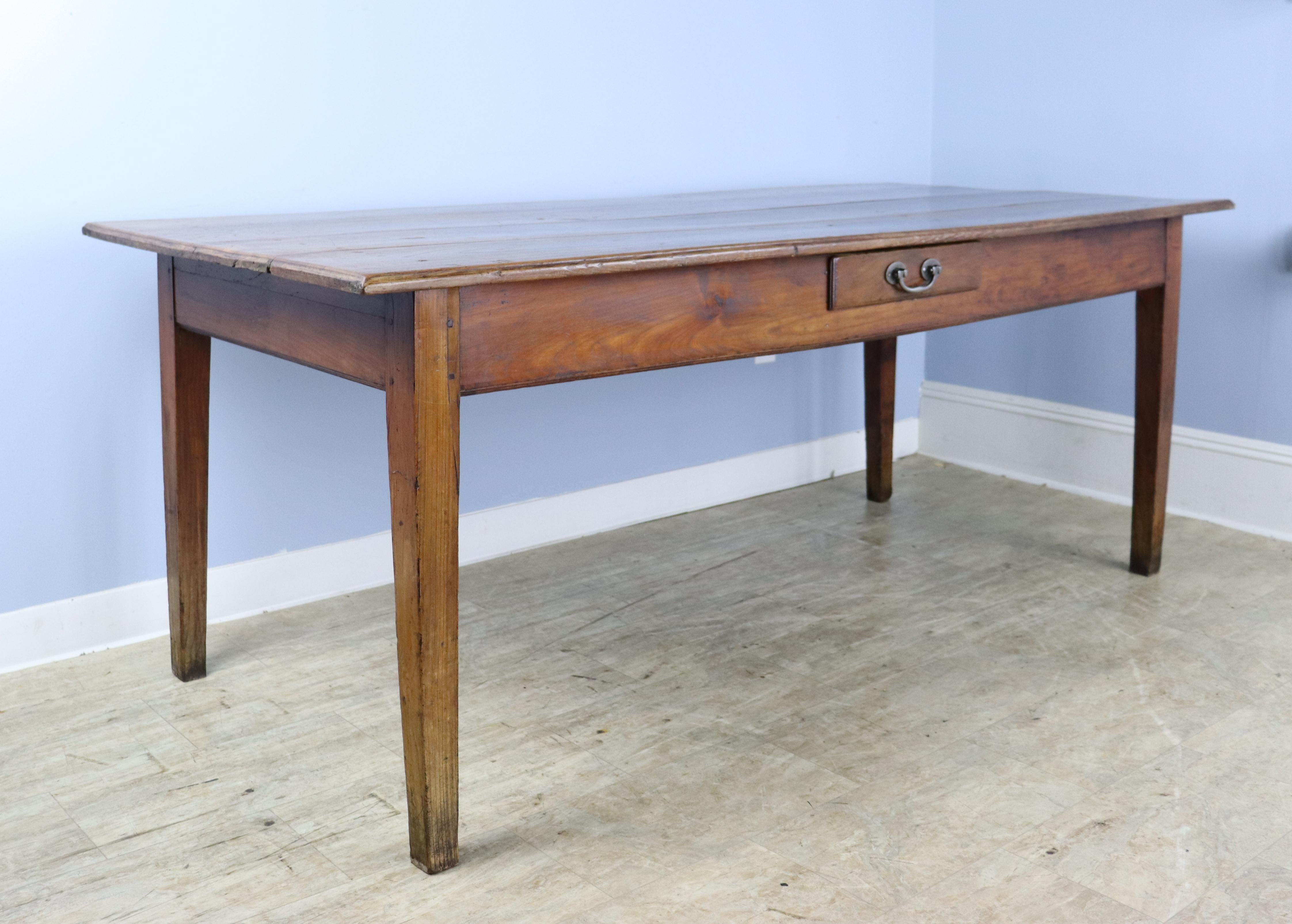 A farm or dining table with a wonderfully grained and colored top. The small beveled edge on the top, along with the single drawer mid-apron, give this table real character. There is slight wear on the top, shown in thumbnails. There are 67 inches