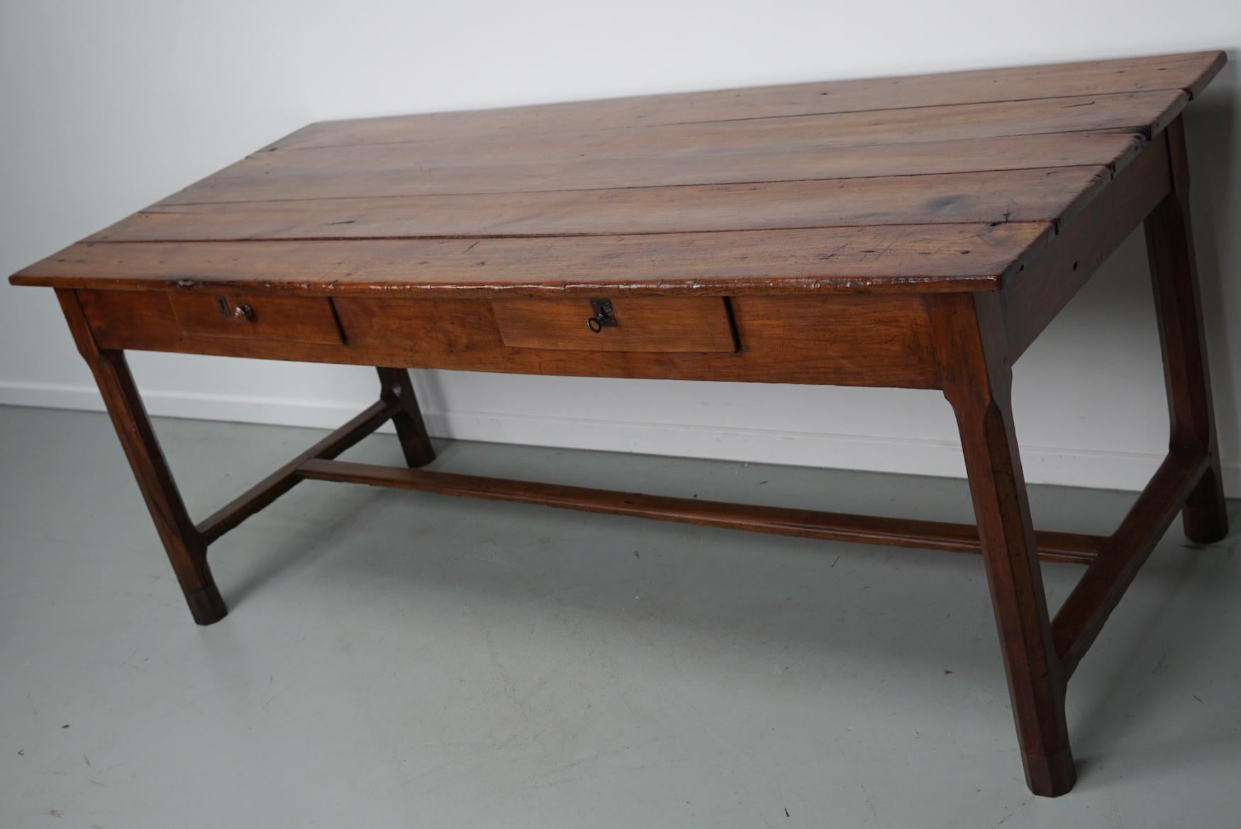 This elegant table was made in Southern France in the mid 19th century. The table was made in solid cherry wood with beautiful grain patterns. It has a very warm color and the table shows many marks of use, old repairs and a has a great patina. The