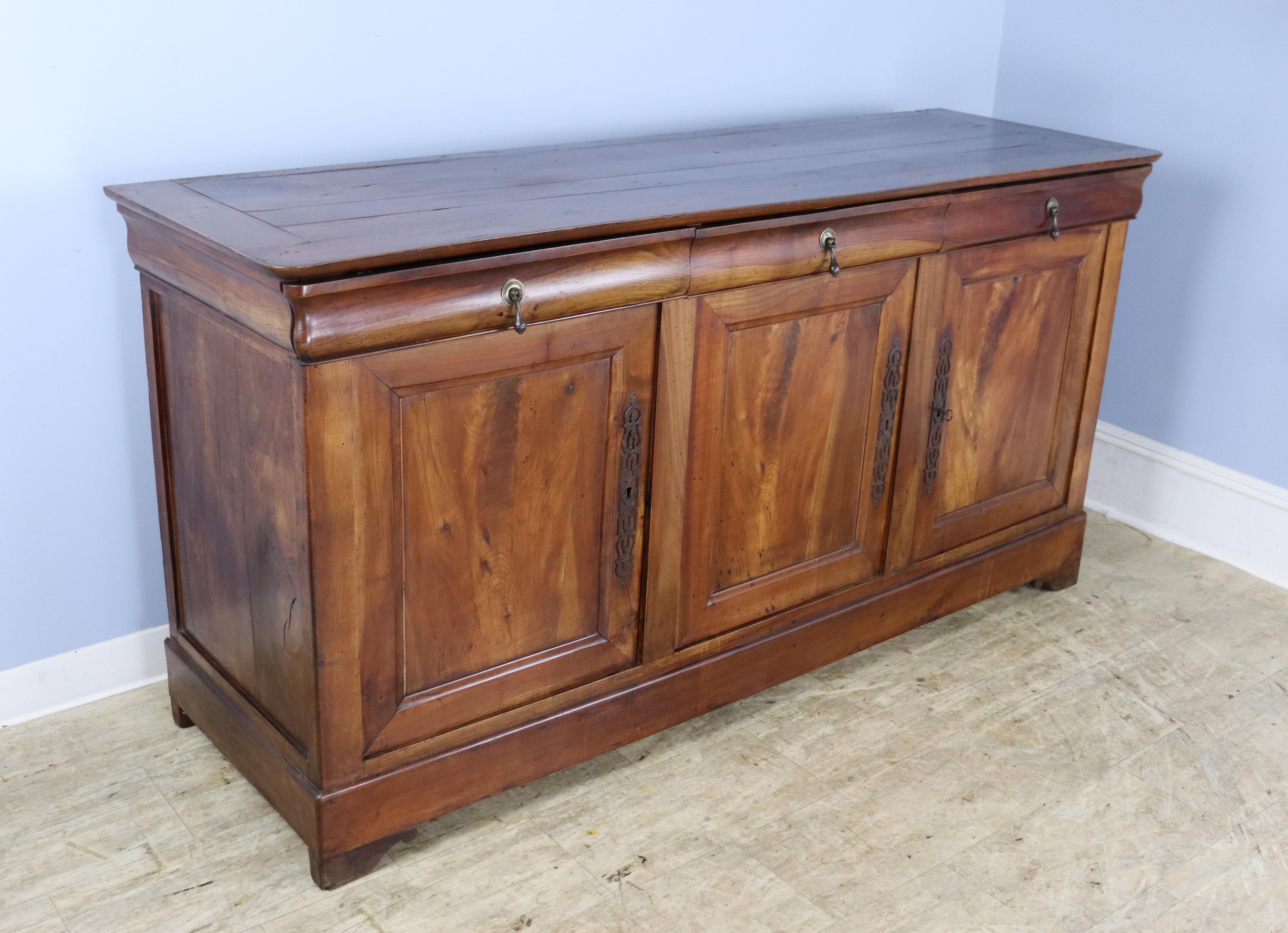 Very good, mid brown cherry three-door enfilade, buffet or sideboard with beautiful patina, highlighted by well grained inset panels on the doors.  Nice stylized feet. The brass hardware original and full of character.  Excellent storage.  All three