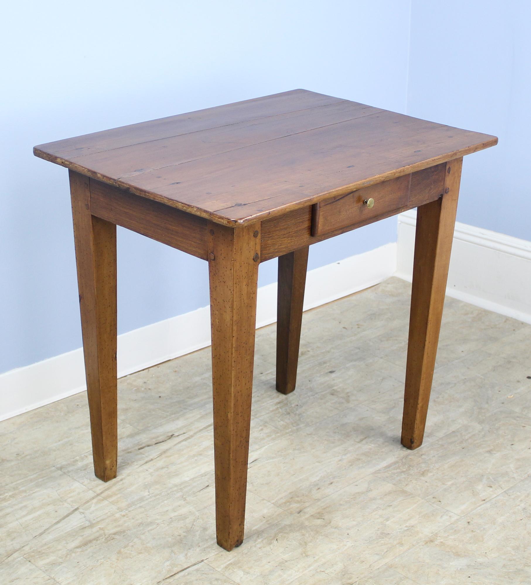 A graceful and sturdy antique French side table in mellow cherry. The piece features elegant tapered legs and a single drawer with hand-wrought cherry knob. Lovely patina and grain.