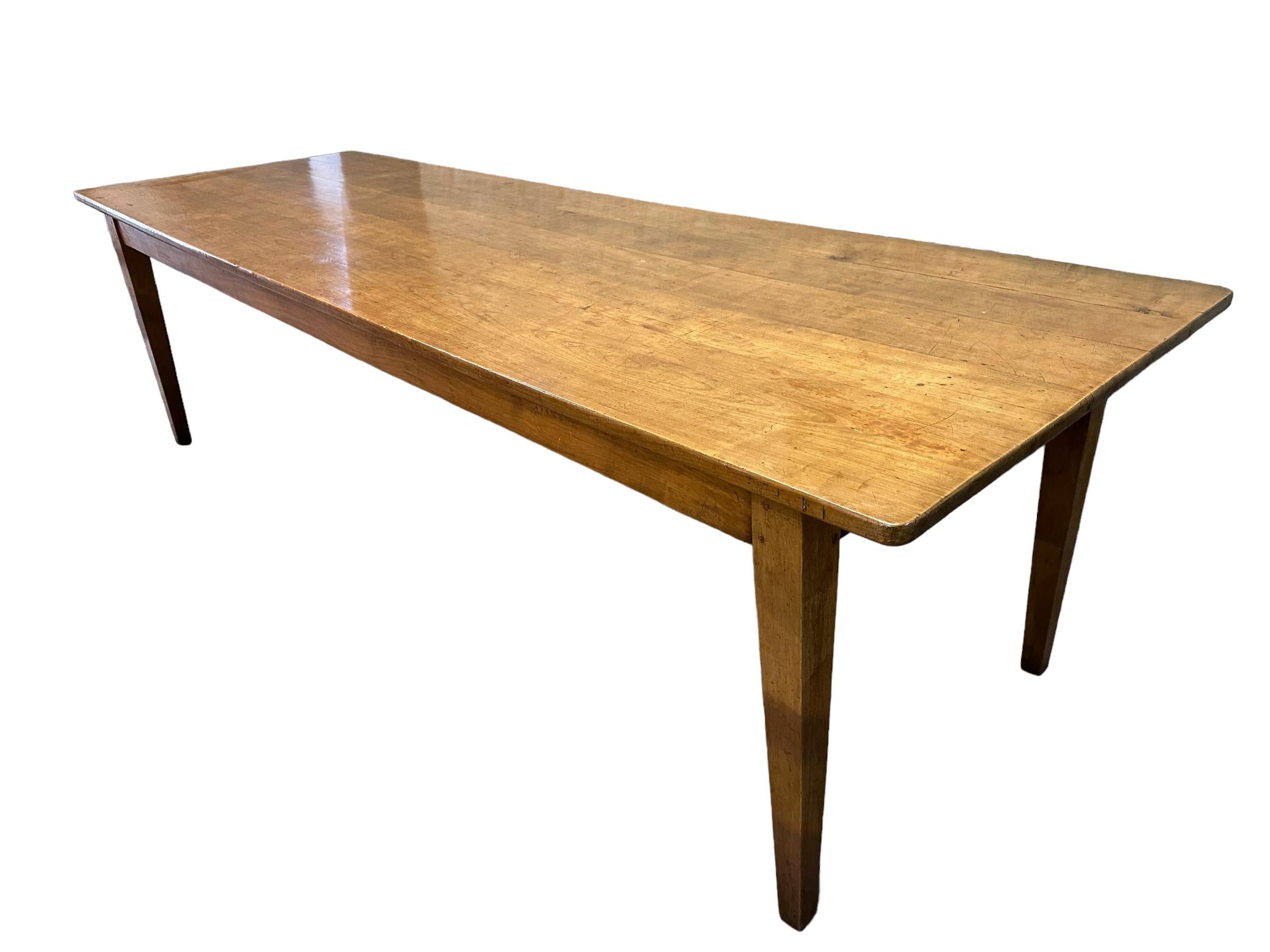 L'image montre une exquise table en cerisier antique avec des pieds effilés et une base solide. La table présente une belle patine qui ajoute du caractère et de la profondeur à son aspect général. La couleur étonnante du bois de cerisier est mise en