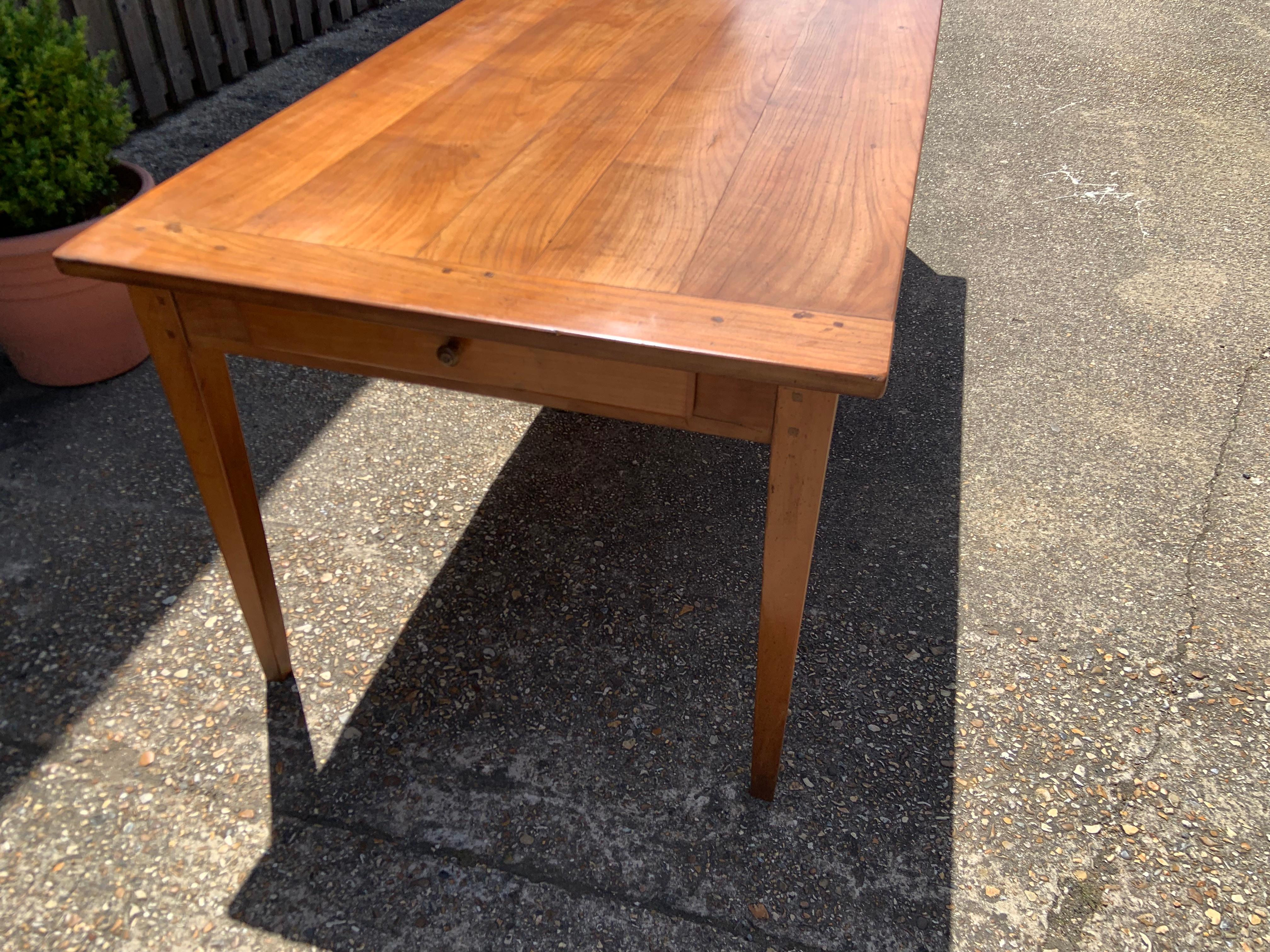 Antique cherry tapered leg dining table with lovely wide top and cleated ends. The table has one good size drawer on one end. The table is a mellow cherry in colour, the table sits on four tapered legs with ample of leg room at each end. The table