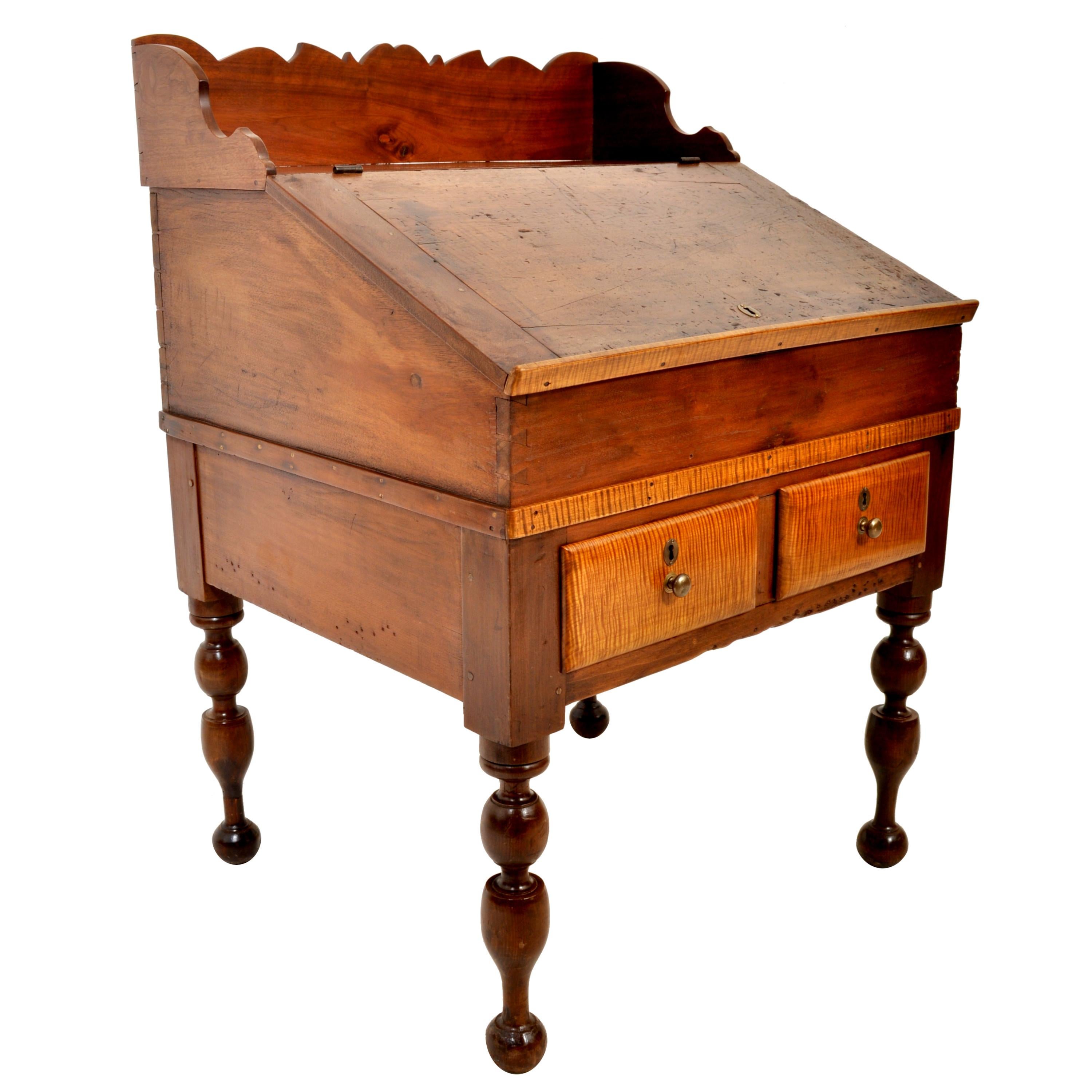 Antique cherry and tiger maple New England, Sheraton, plantation desk/secretary, circa 1820. To the back is a shaped gallery, below is a slant front hinged writing surface enclosing drawers and pigeon holes, the base having two drawers, the desk