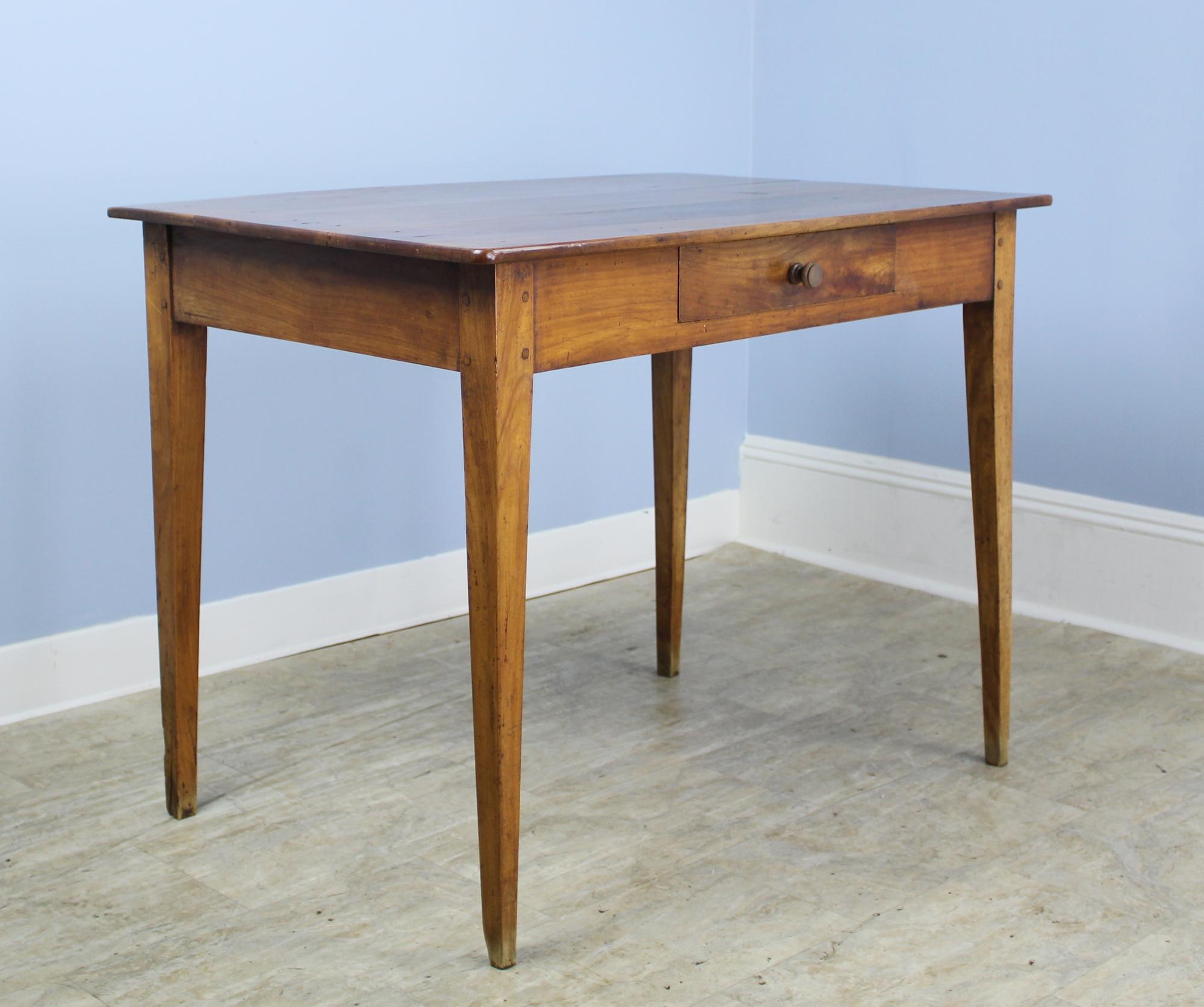 A graceful French antique writing table in vibrant cherry. Elegant tapered legs and a comfortable 24