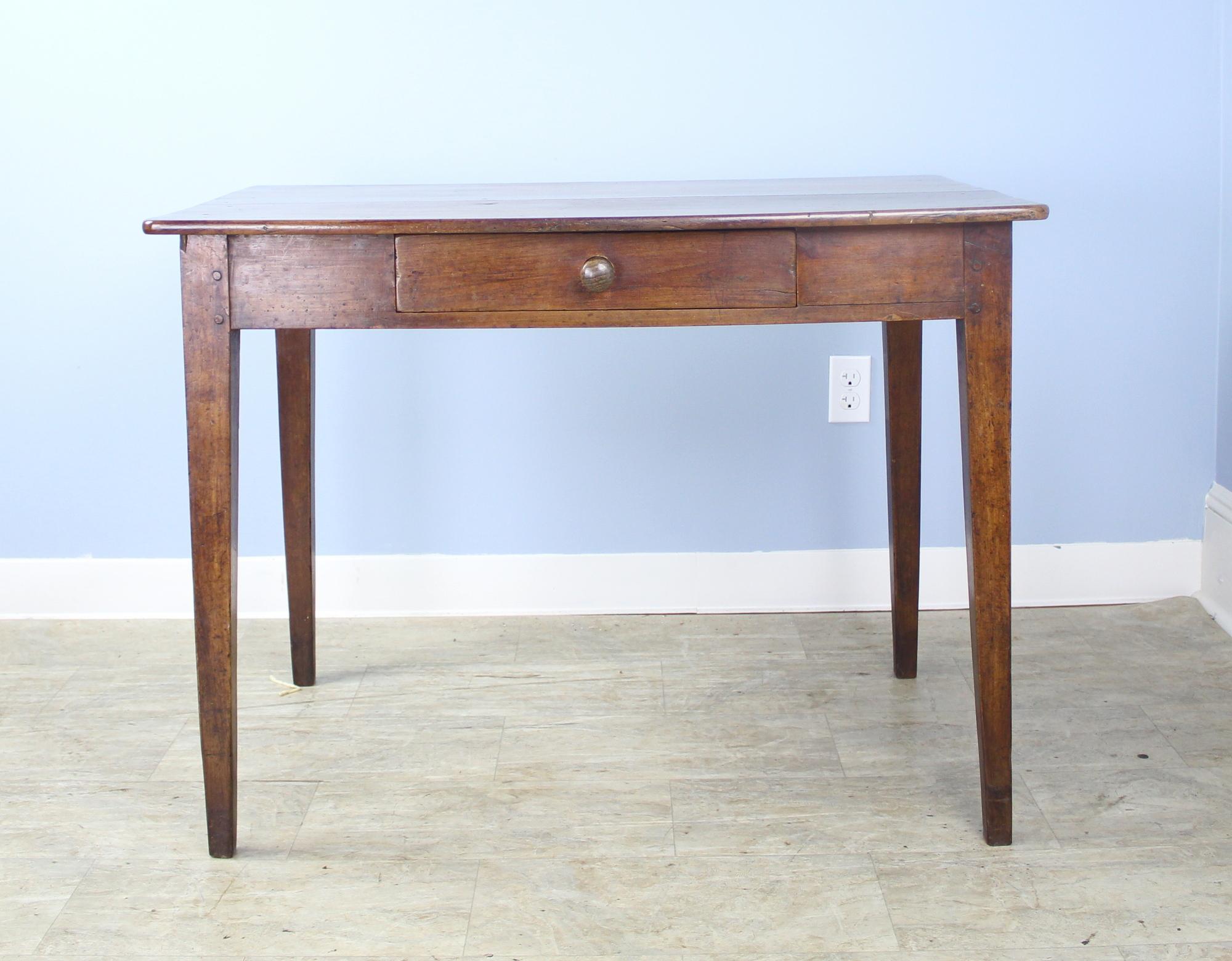 A graceful French antique writing table in vibrant cherry. Elegant tapered legs and a comfortable 24.5