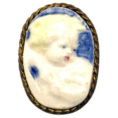 Broche ancienne d'enfant putto en forme de chérubin avec cadre en céramique et laiton