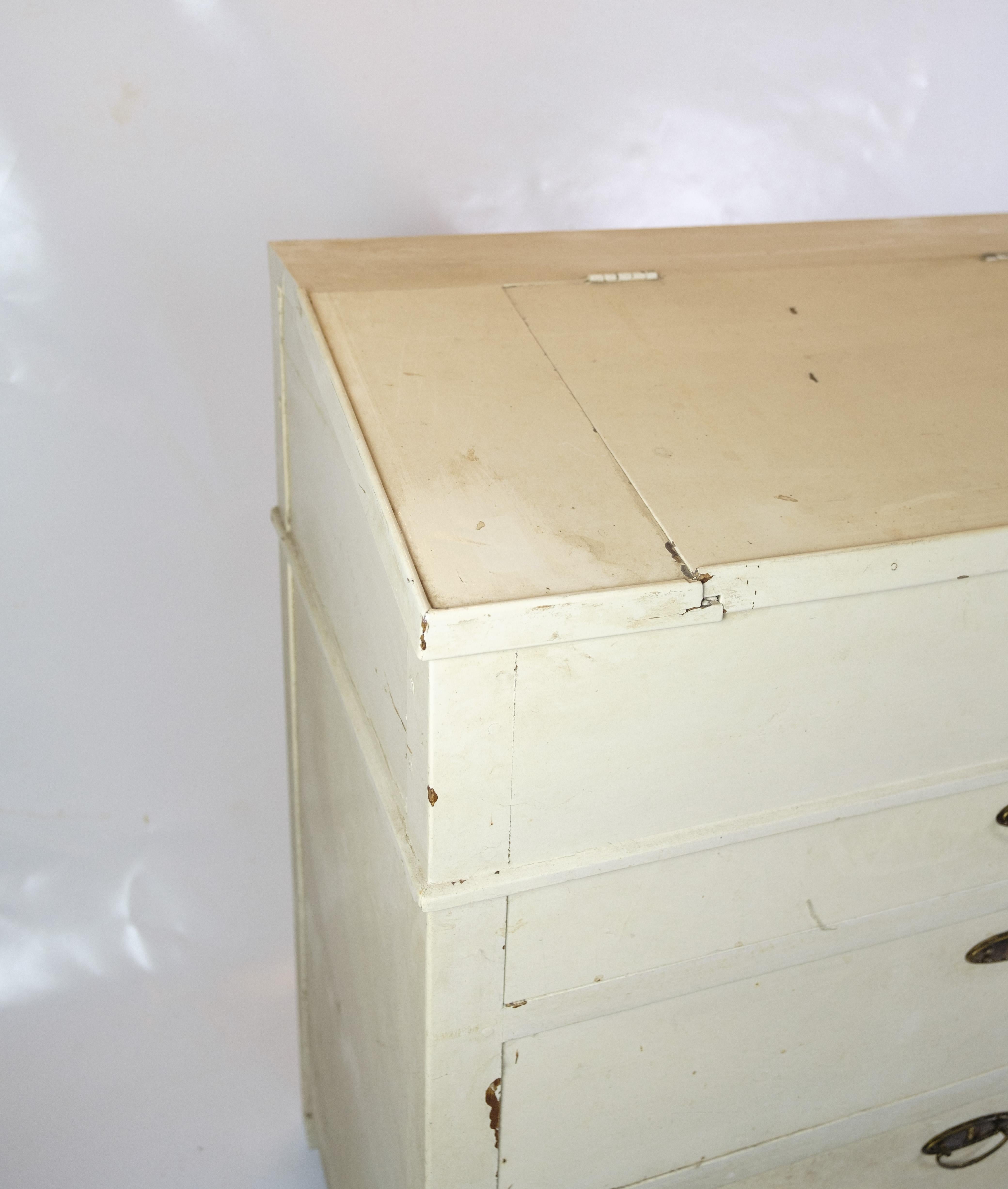Diese antike Kommode/Schreibtisch aus der Zeit um 1890 ist ein beeindruckendes Stück Möbelgeschichte. Mit seiner weiß lackierten Oberfläche strahlt er zeitlose Eleganz und Charme aus. Die fünf geräumigen Schubladen bieten praktischen Stauraum für