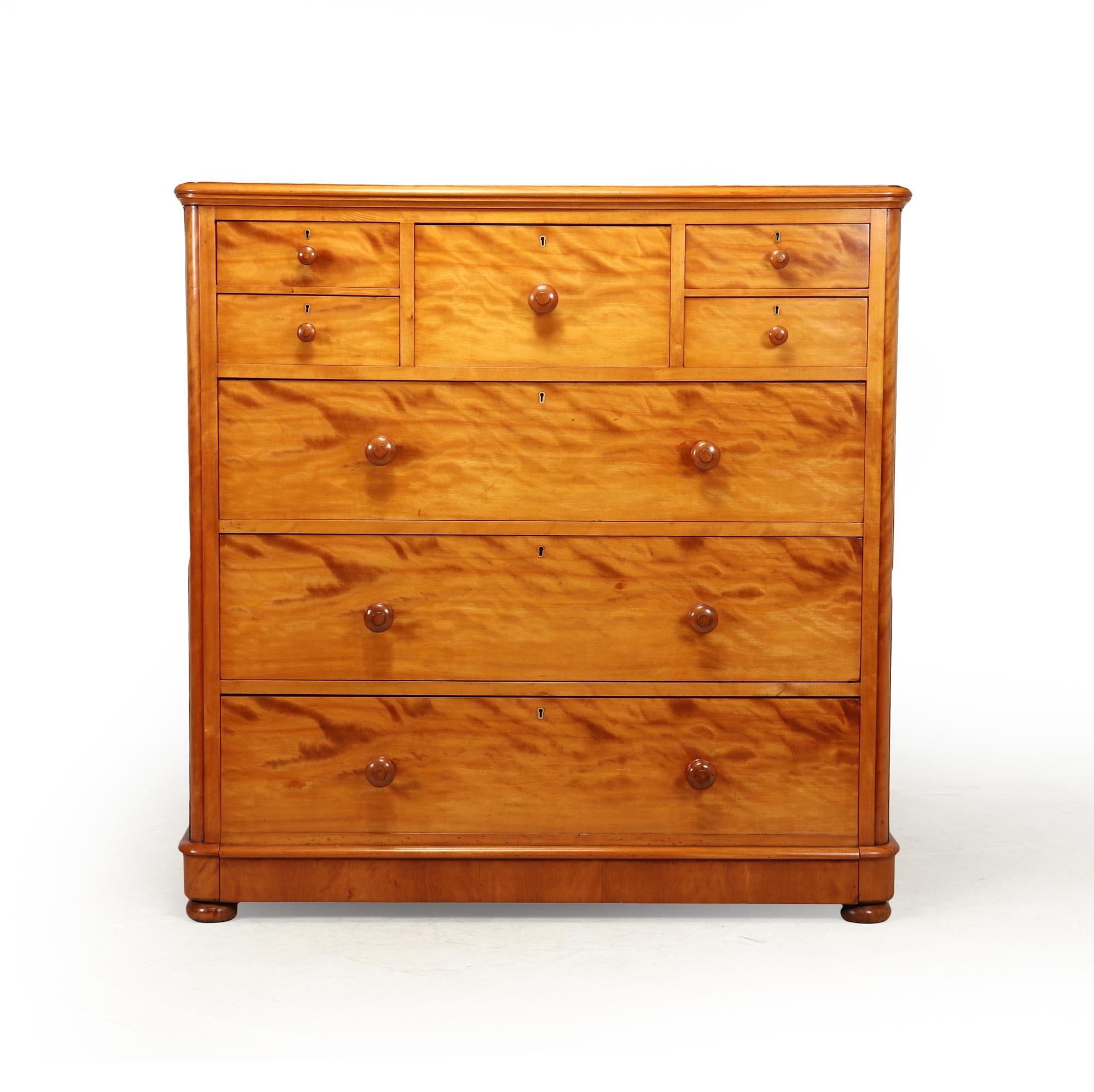 A substantial sized English chest of drawers circa 1870 in Satin Birch produced by Maple & Co. The top middle drawer is fully stamped Maple & Co. and all locks are stamped VR for Queen Victoria This chest is of rounded corner design, and gives a