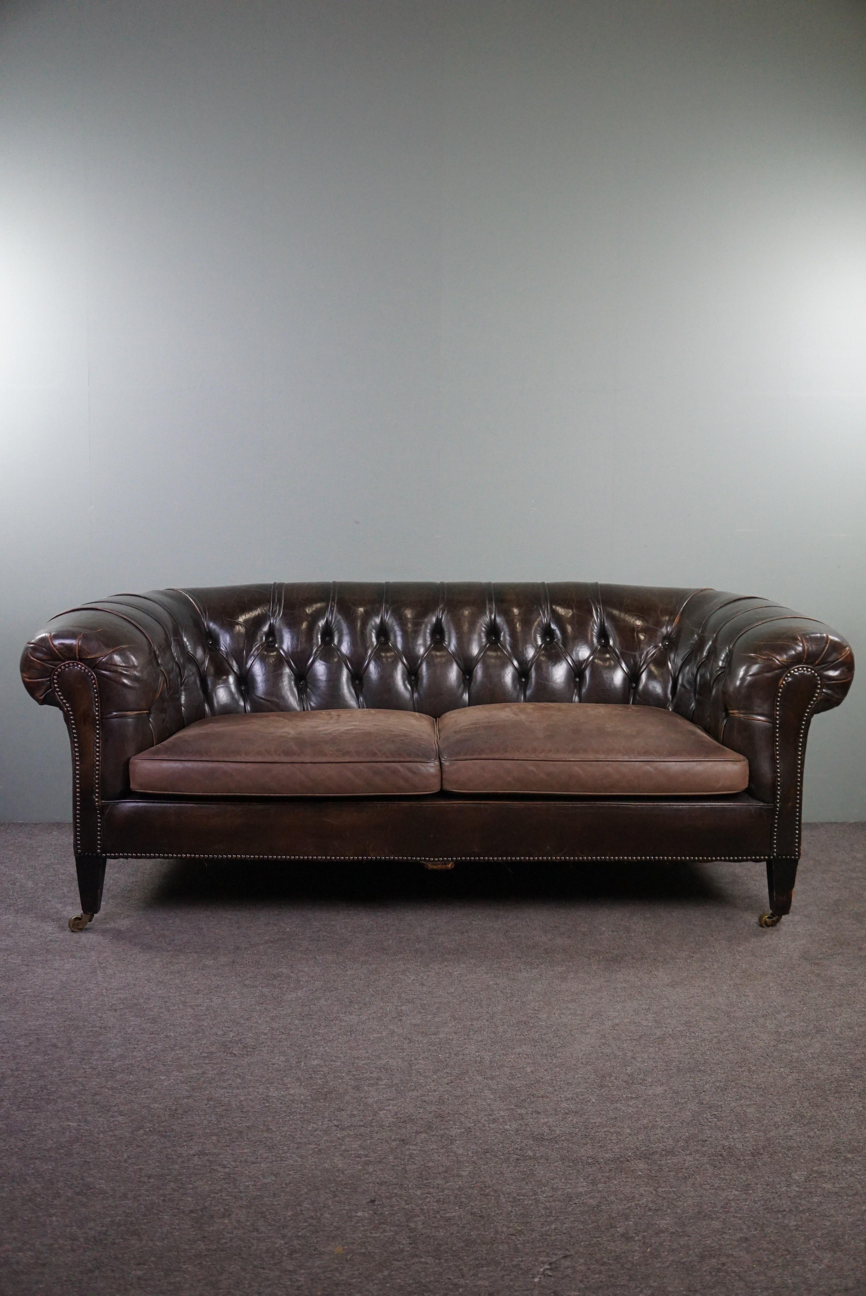 
With pride we offer you this wonderfully comfortable patinated antique 2.5-seater Chesterfield sofa in stunning condition due to its patina.

This Chesterfield sofa features a beautiful tufted seat, a rich deep color, and stands on slender wooden