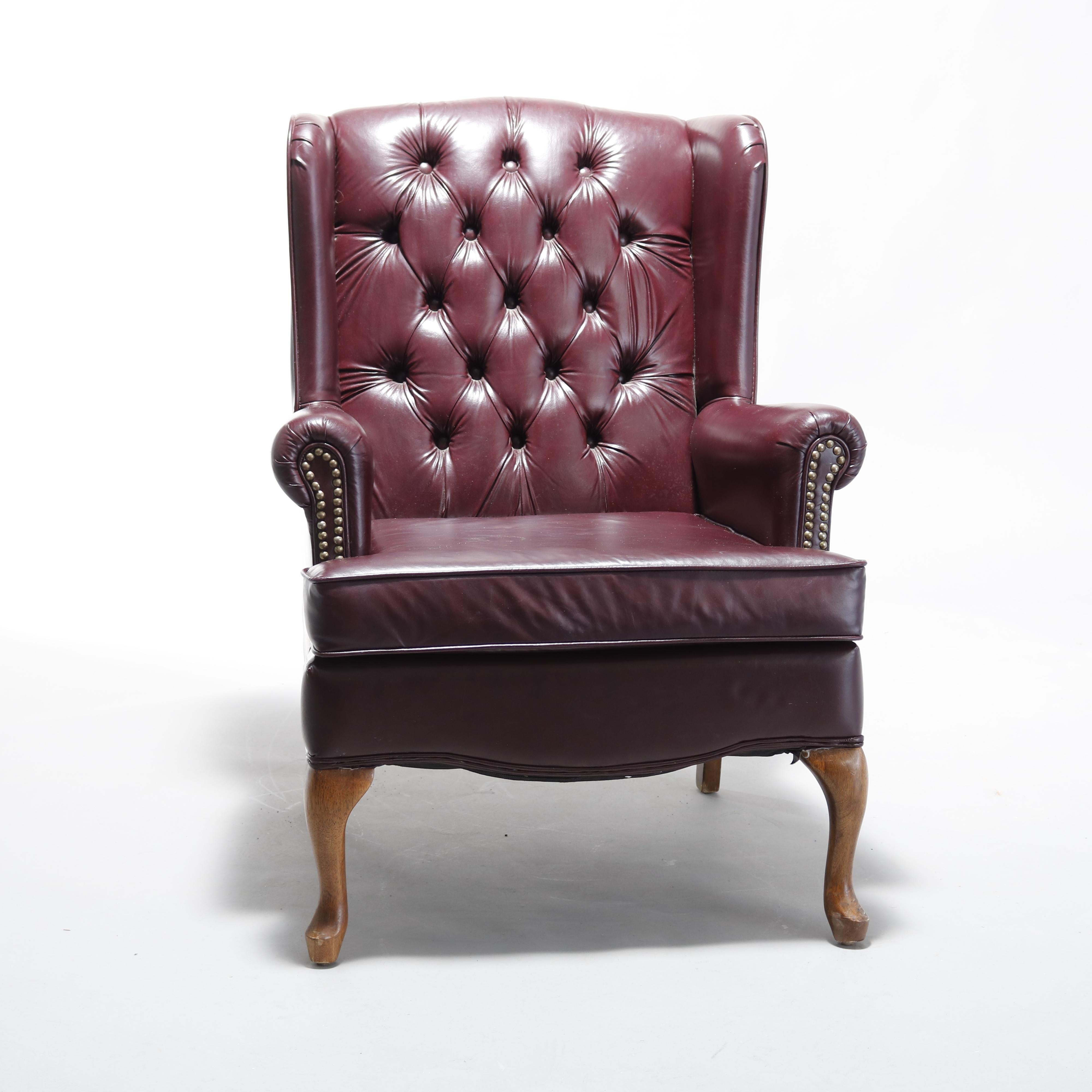 An antique Chesterfield wing back chair offers tufted leather with scroll forma arms and raised on carved cabriole legs, 20th century.

Measures: 39.5