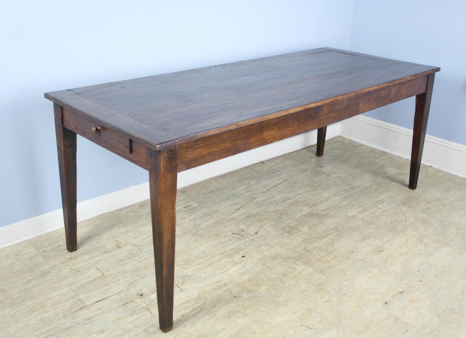 A simple classic chestnut farm table with beautiful grain and patina. Good tapered legs and breadboard ends. The apron height of 25 inches is generous for knees and there are 73.5 inches between the legs on the long side.