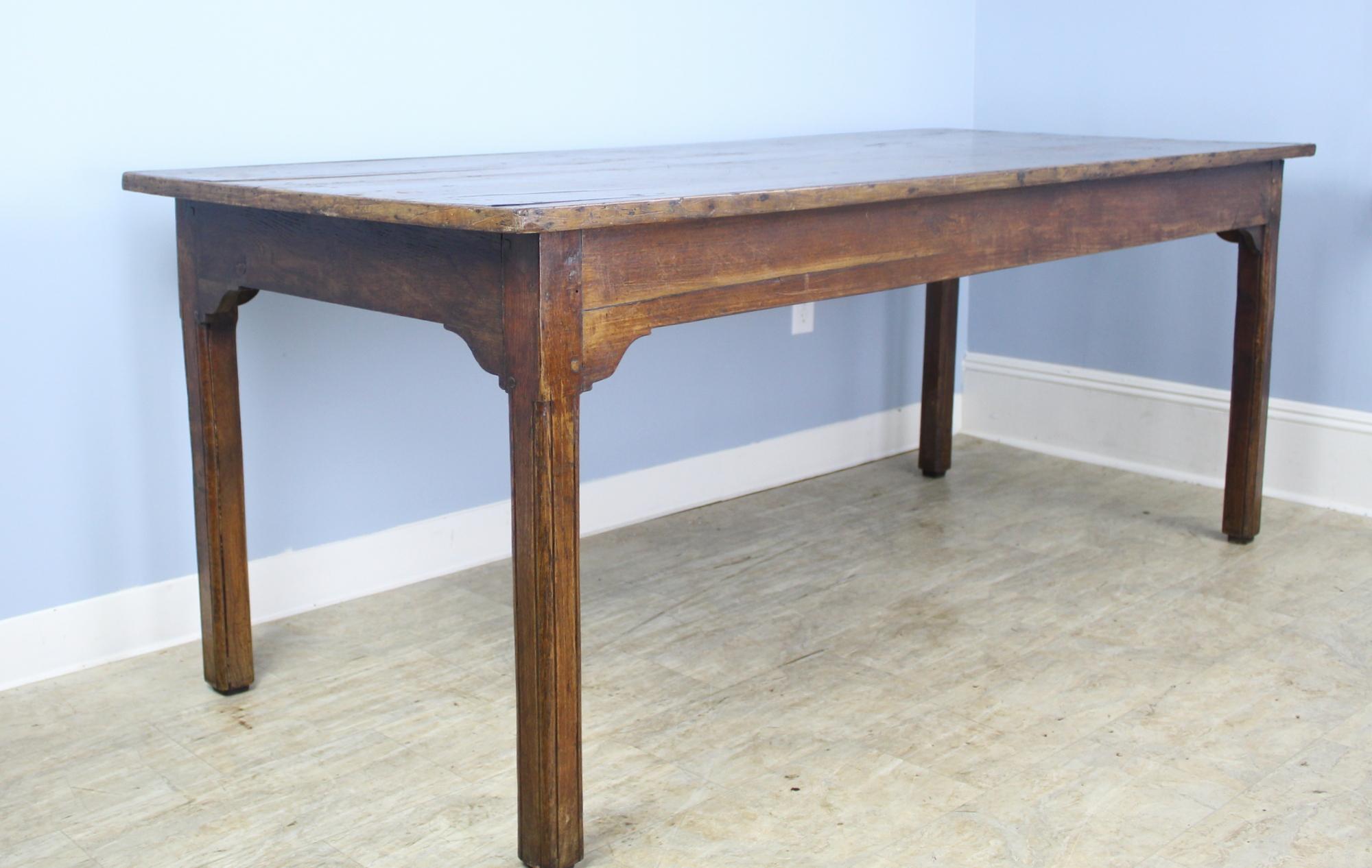 A charming French chestnut farm table with a decorative wood trimmed edge. The mellow chestnut has wonderful color and patina, highlighted by naturalistic grain lines. Sweetly carved corners on the apron add an additional design note, as do the