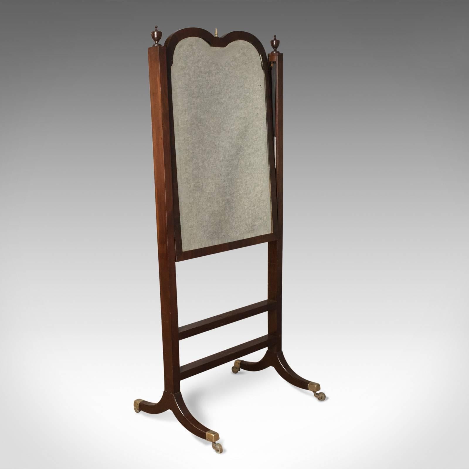 This is an antique cheval mirror, an English, Regency, tilting dressing mirror in mahogany stand dating to circa 1820.

Quality, heavy hand bevelled, shaped mirror plate
Mounted in humped mahogany frame
Topped with brass spire finial
Panelled