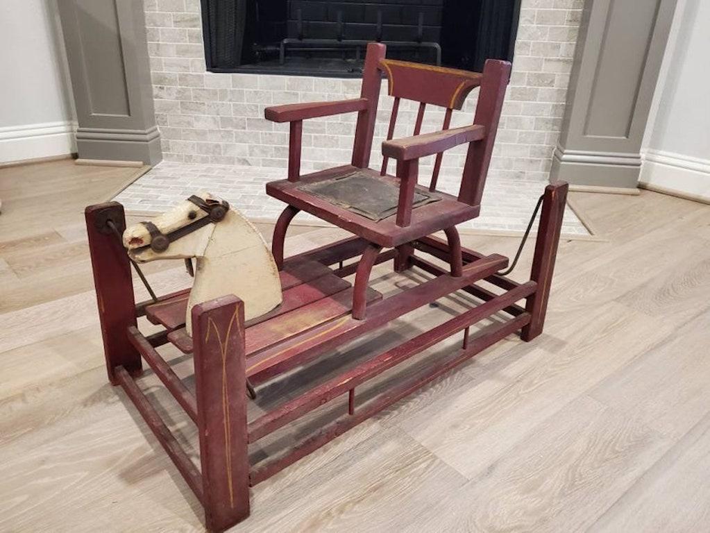 A rare and unusual form antique American early wooden child’s toy horse rocker with cushioned seat and beautiful patina. Dating to the mid-19th century, the primitive rocker having a wooden four poster base that's hand painted red with gold accents,