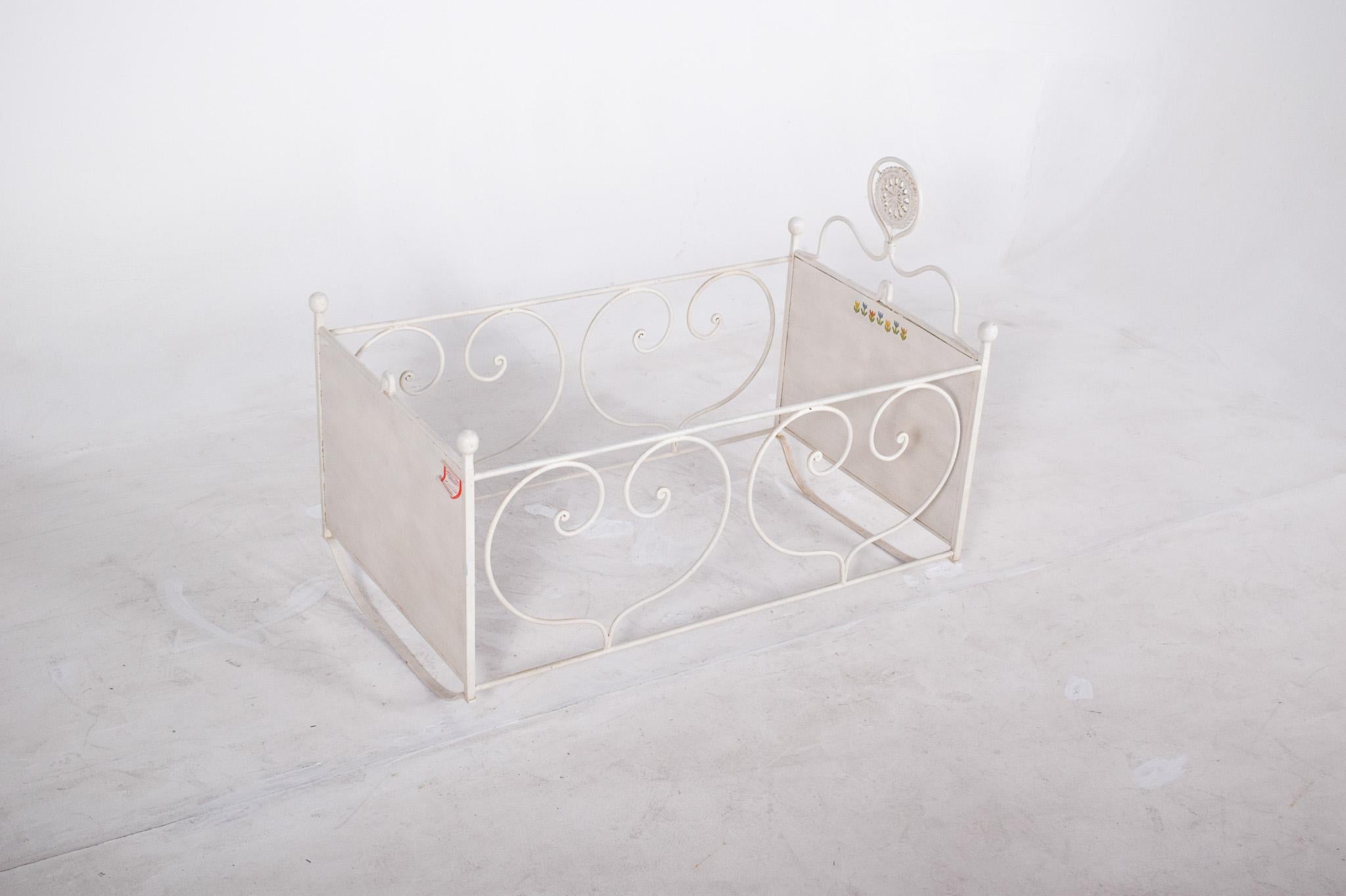 Lit d'enfant en fer peint en blanc. Avec une structure légère et délicate aux formes courbes et symétriques. Le design rappelle le style vintage ou provençal, très courant dans les meubles pour enfants des premières décennies du XXe siècle. Les