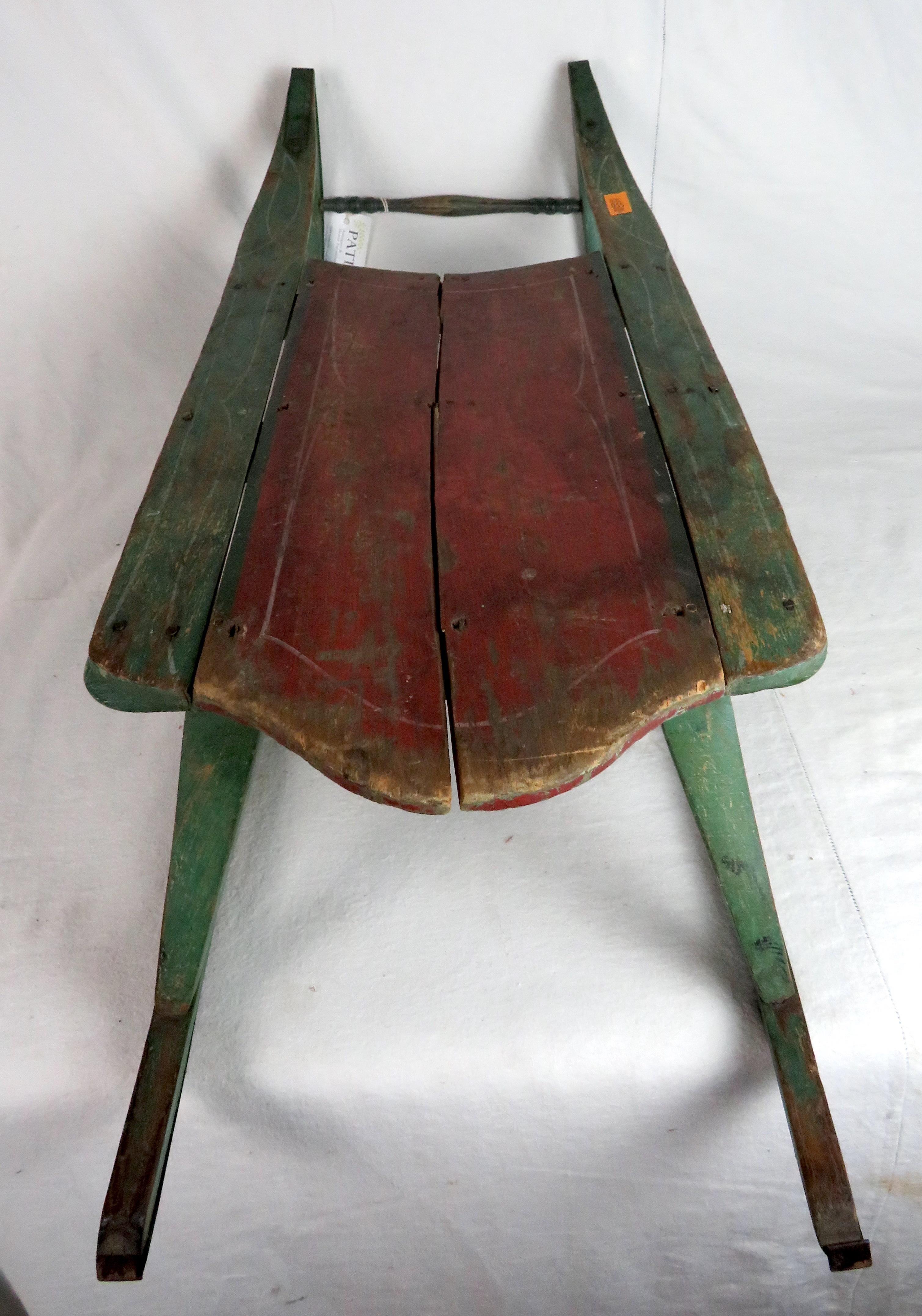 Antique Child's snow sled with green painted body and red seat.