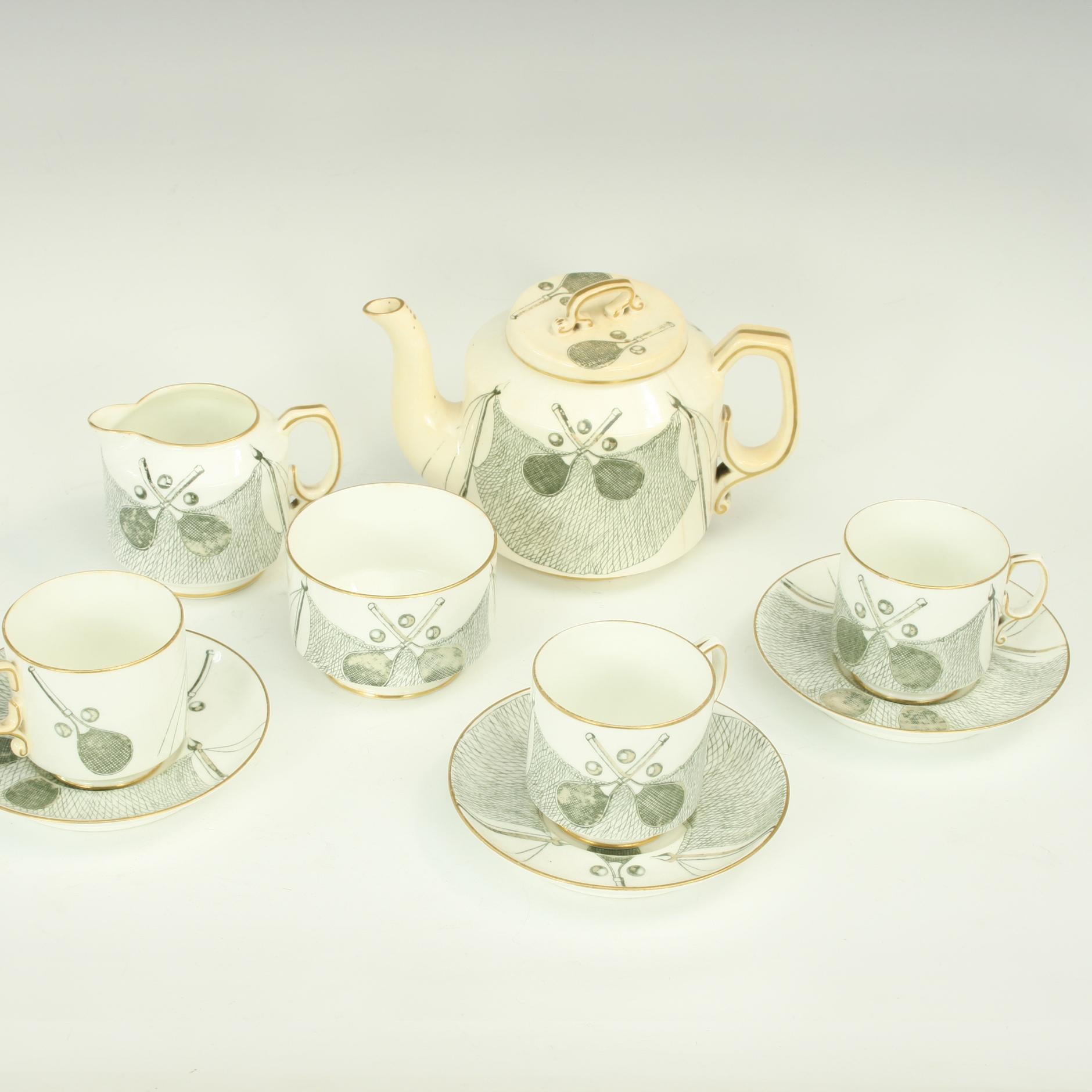 This is a very rare China tennis tea set by George Jones & Sons. The set comprises of a tea pot, three cups with saucers, a sugar bowl and a milk jug. Each item has a gilt rim with tennis rackets, balls and net on them. The sugar bowl has a slight