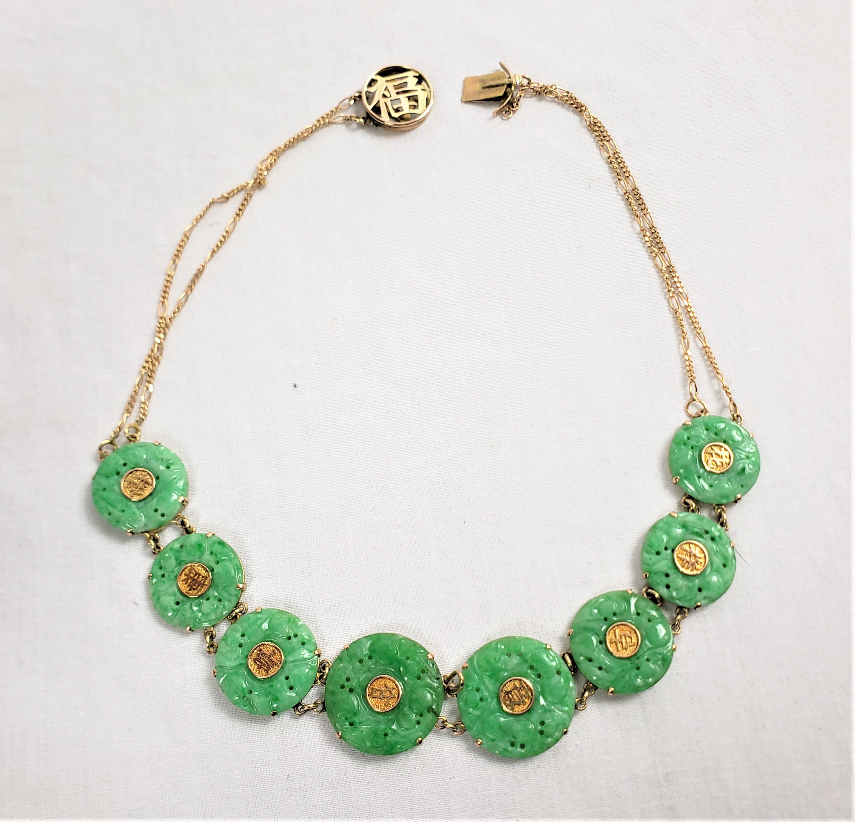This antique necklace is signed by an unknown maker and originates from China, dating to approximately 1920 and done in the period Chinese Export style. The necklace is composed of 14 karat yellow gold and carved green jade floral discs with gold