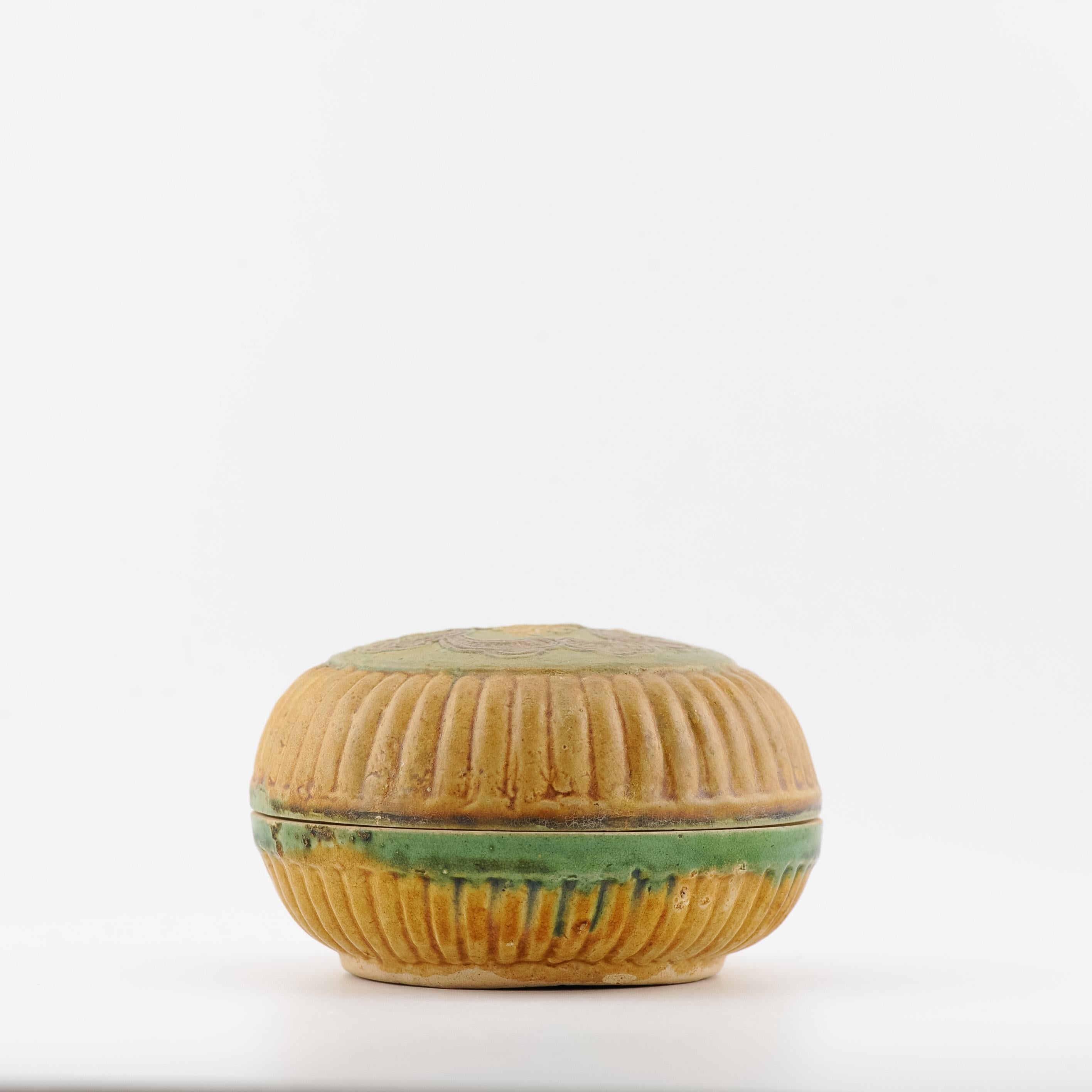 This is a small Ming dynasty moulded sancai funerary covered box with ribbed sides. On top of the covered box, it has a moulded design of flowers. It has a low footrim with a mildly recessed base. It also has a square seal mark.


Condition
minimal