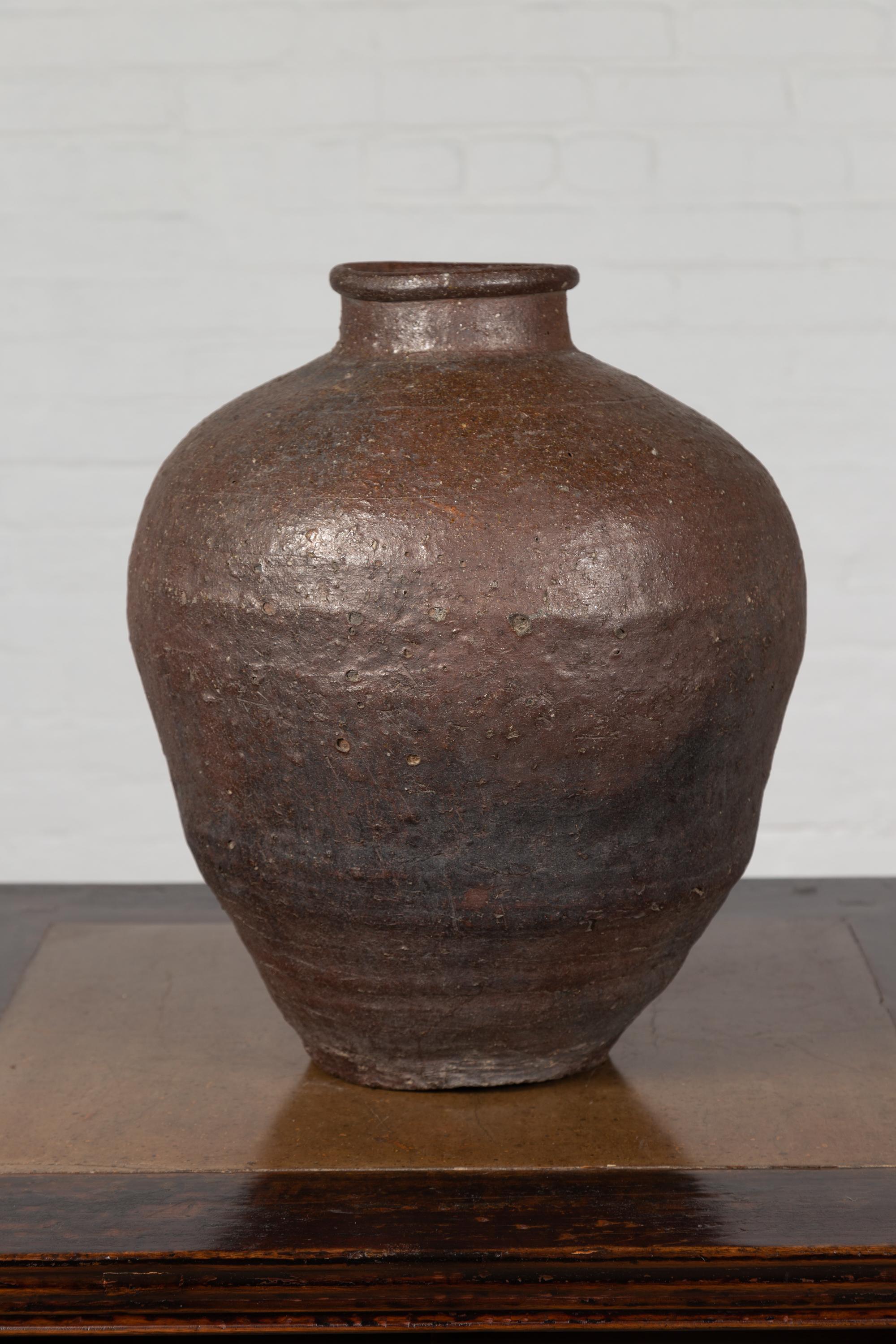 An antique Chinese grain storage urn from the 19th century, with nicely weathered appearance. Born in China during the 19th century, this grain storage urn charms our eyes with its nicely weathered appearance, imperfect lines and brown color with