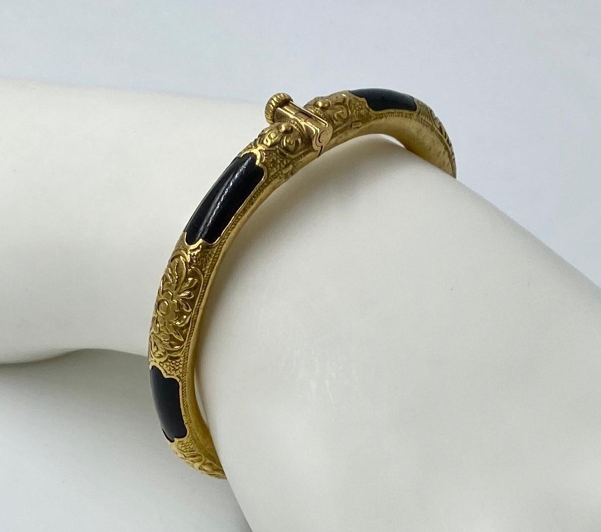 A magnificent antique circa 1930 Chinese Hinged Bangle Bracelet in beautifully engraved 22 Karat Yellow Gold with Black Coral adornments.  The bracelet has six 22 karat gold sections with engraved flower and leaf designs.  The beautiful gold