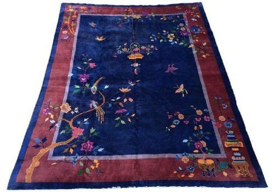 A stunning example of a vintage Art Deco carpet, hand woven in Tianjin, north-east China, circa 1920’s with a simple design of floral sprays, hanging lantern, birds and butterflies on a navy blue field and burgundy red border.
Size: 3.57m x 2.69m