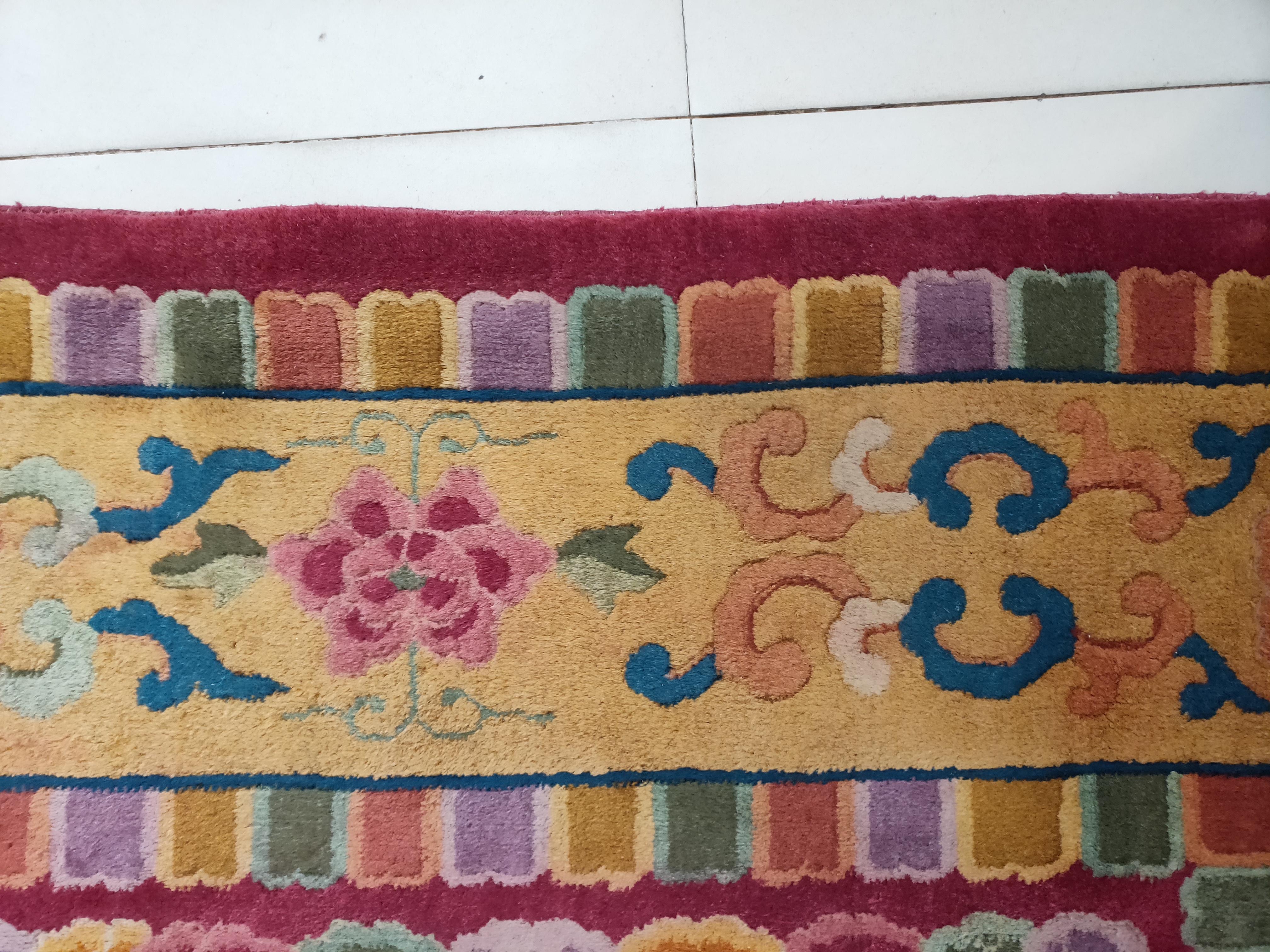 Not all Art Deco Chinese carpets are restrained or Minimalist. Nine colorful dragons fiercely writhe on a brisk red field among flaming pearls and cloud knots. A rainbow wave pattern bounds the action within a gold main band with rosettes, and
