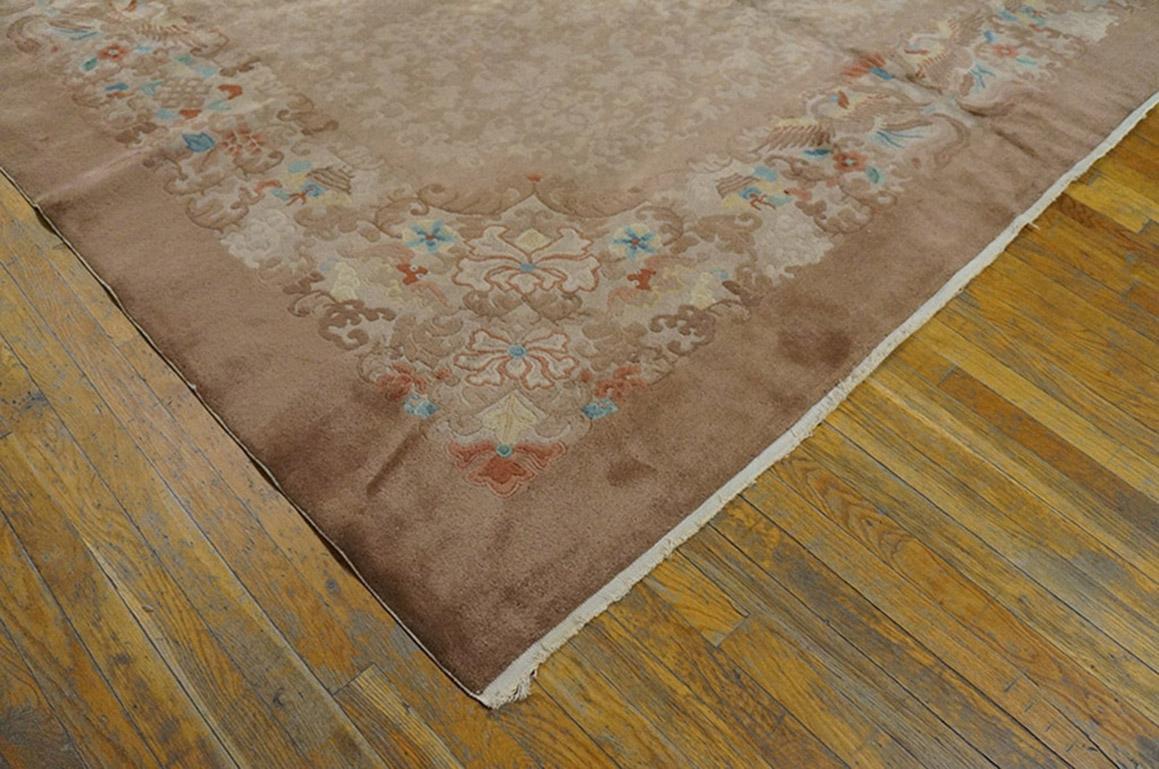 This is a multiply peach-toned Peking interwar carpet in a cartouche-shaped field with knots, leaves and palmettes, framed by a border containing paired feng-huang birds (phoenixes) and more knots and leaves. Semi-tone-on-tone palette, all-over