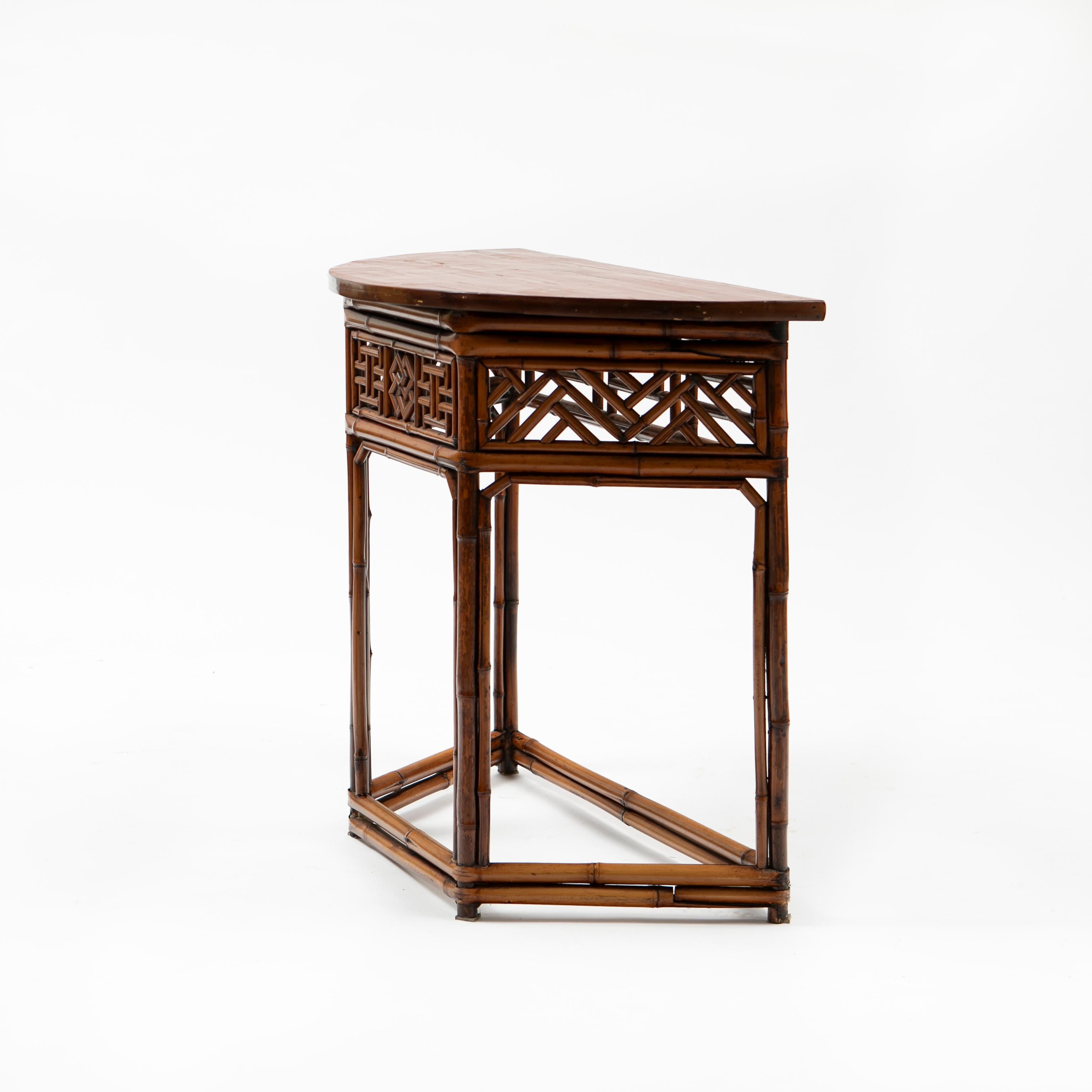 Elegante table demilune chinoise en bambou avec un design géométrique ajouré sur 4 côtés et un plateau en bois laqué rouge en forme de demilune.
État d'origine avec une patine naturelle liée à l'âge, rehaussée d'une finition laquée transparente.