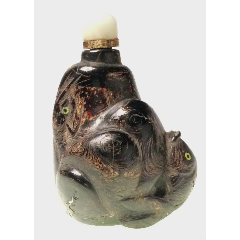 Antique Chinese black coral “sea pine” snuff bottle of a rocky outcropping with a fish and crayfish in relief, 4 inset green shell eyes, hollowed interior. Jadeite stopper with brass collar, (No spoon), flat base. Excellent condition. 2-3/4 in. high