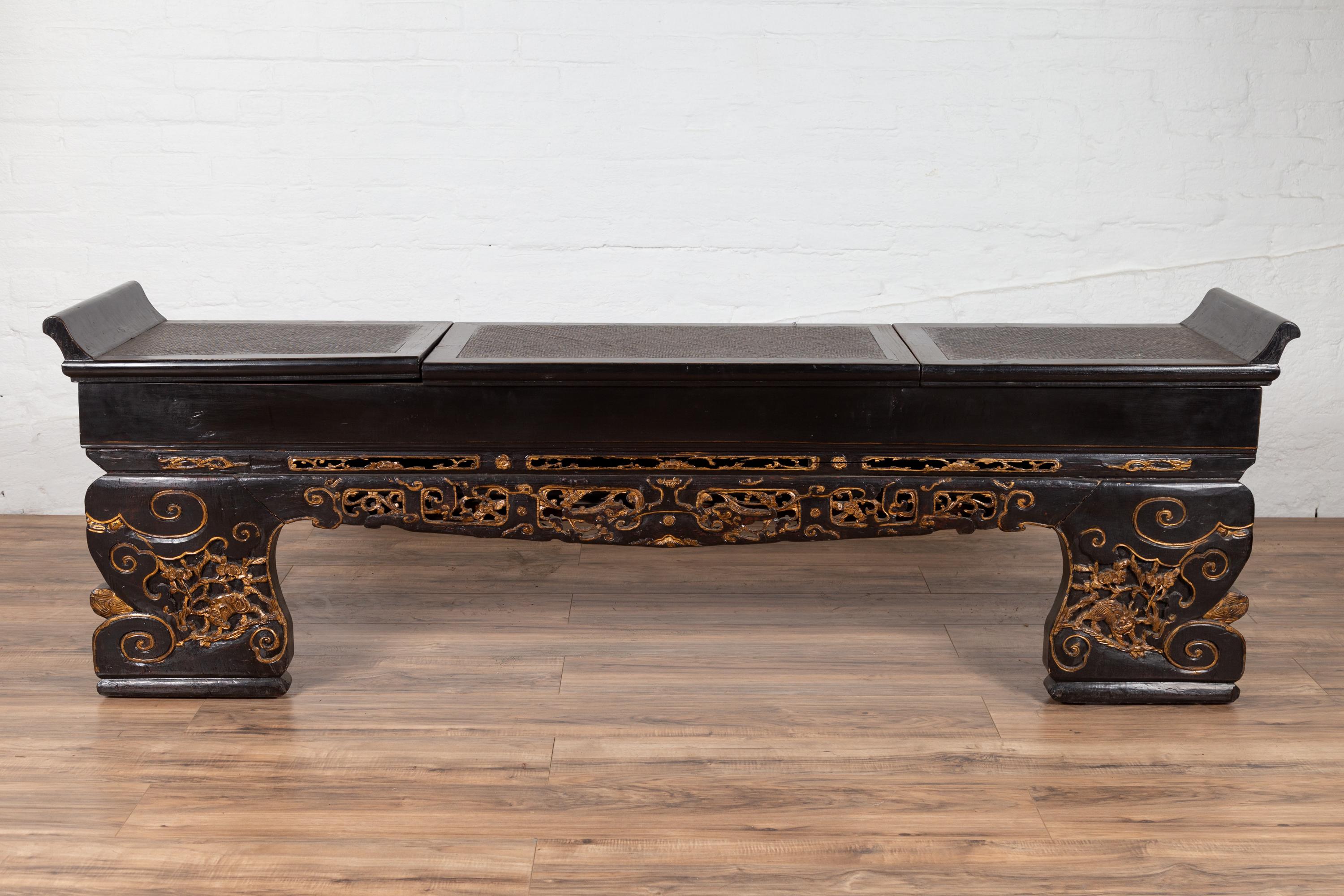 An antique Chinese low console table from the early 20th century with black lacquer finish gilded accents, hidden storage and everted flanges, perfect to be used as a bench. We currently have two pieces available, priced and sold individually. Born