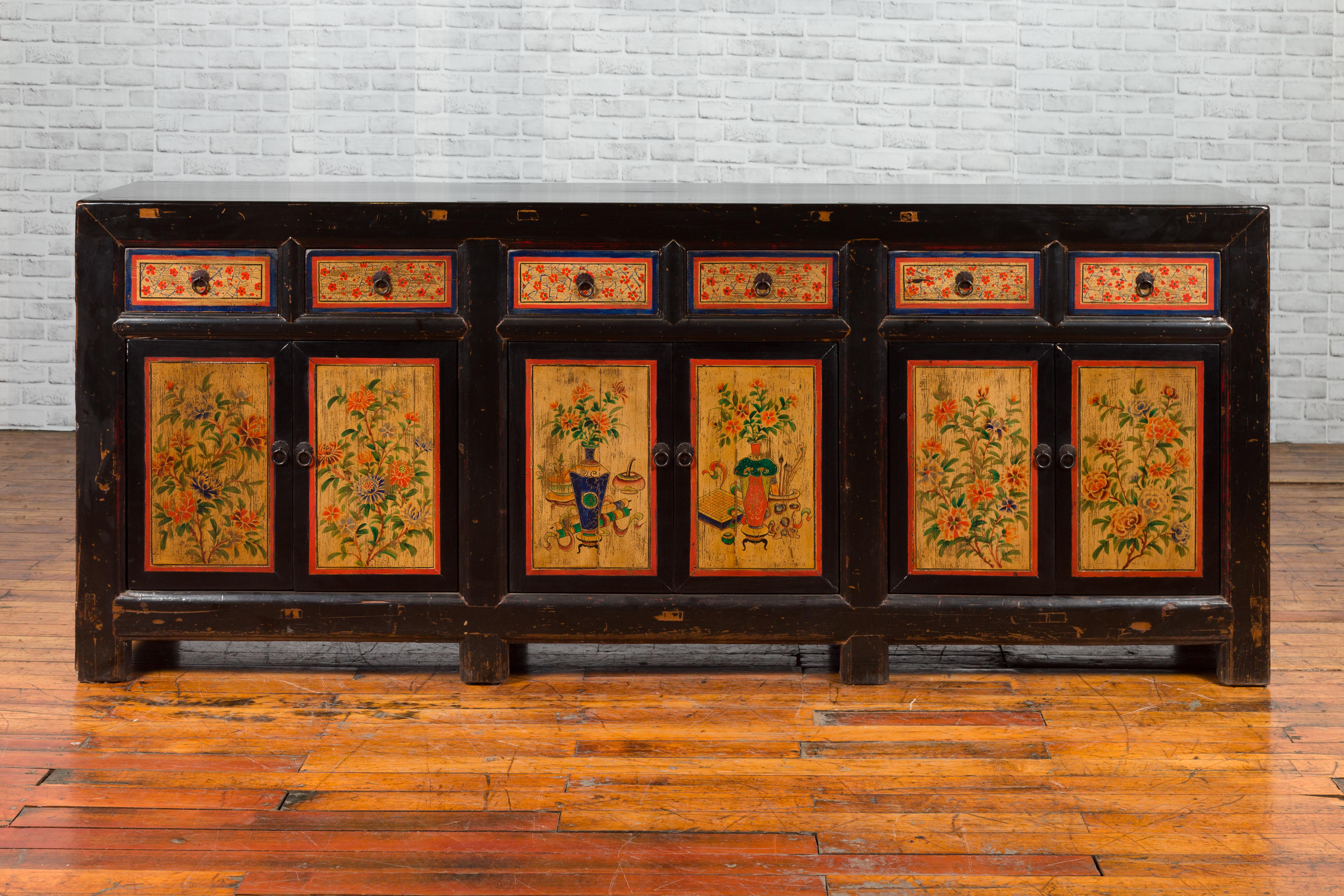 A Chinese black lacquered Gansu sideboard from the early 20th century, with hand painted floral and vase motifs. Created in the North-Center province of China, called Gansu during the early years of the 20th century, this sideboard features a black